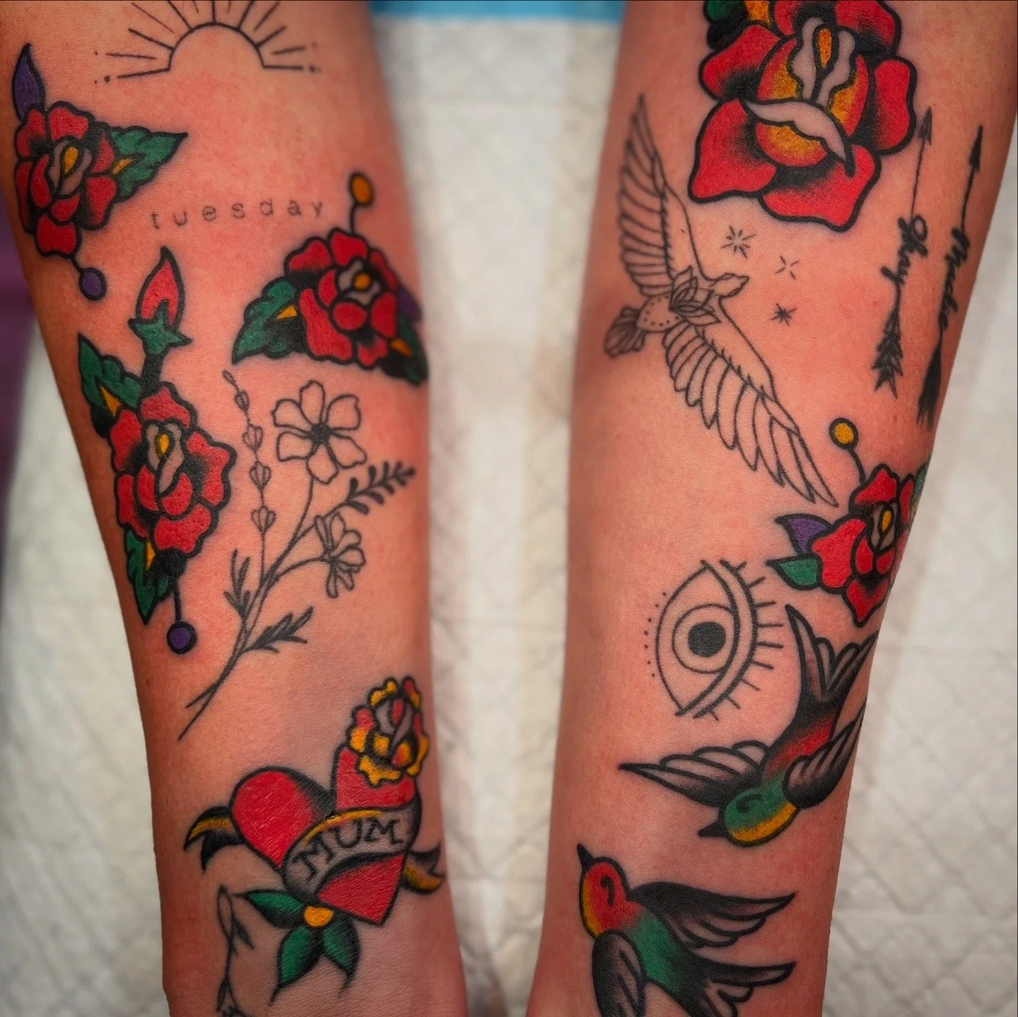 Tattoo sleeve featuring red roses, hummingbirds, an eye, and the word "Tuesday."