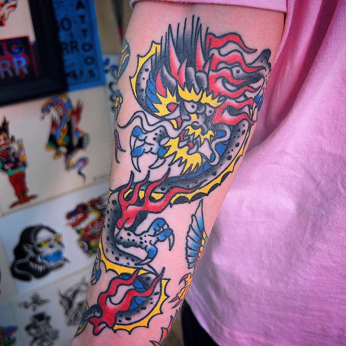 Tattoo of a traditional Japanese dragon with black, red, yellow, and blue colors on a person's forearm.