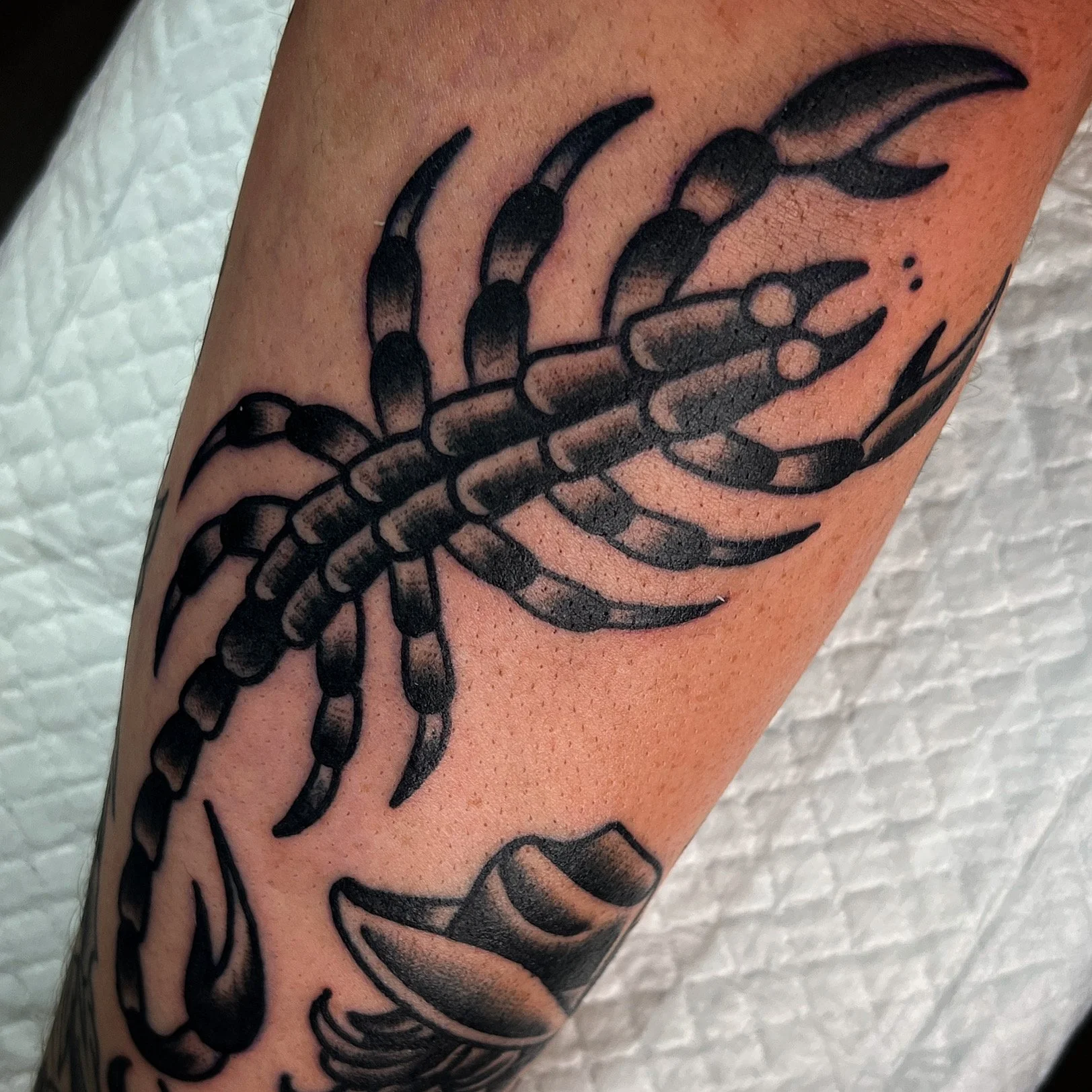 Black and grey tattoo of a lobster on a person's arm.