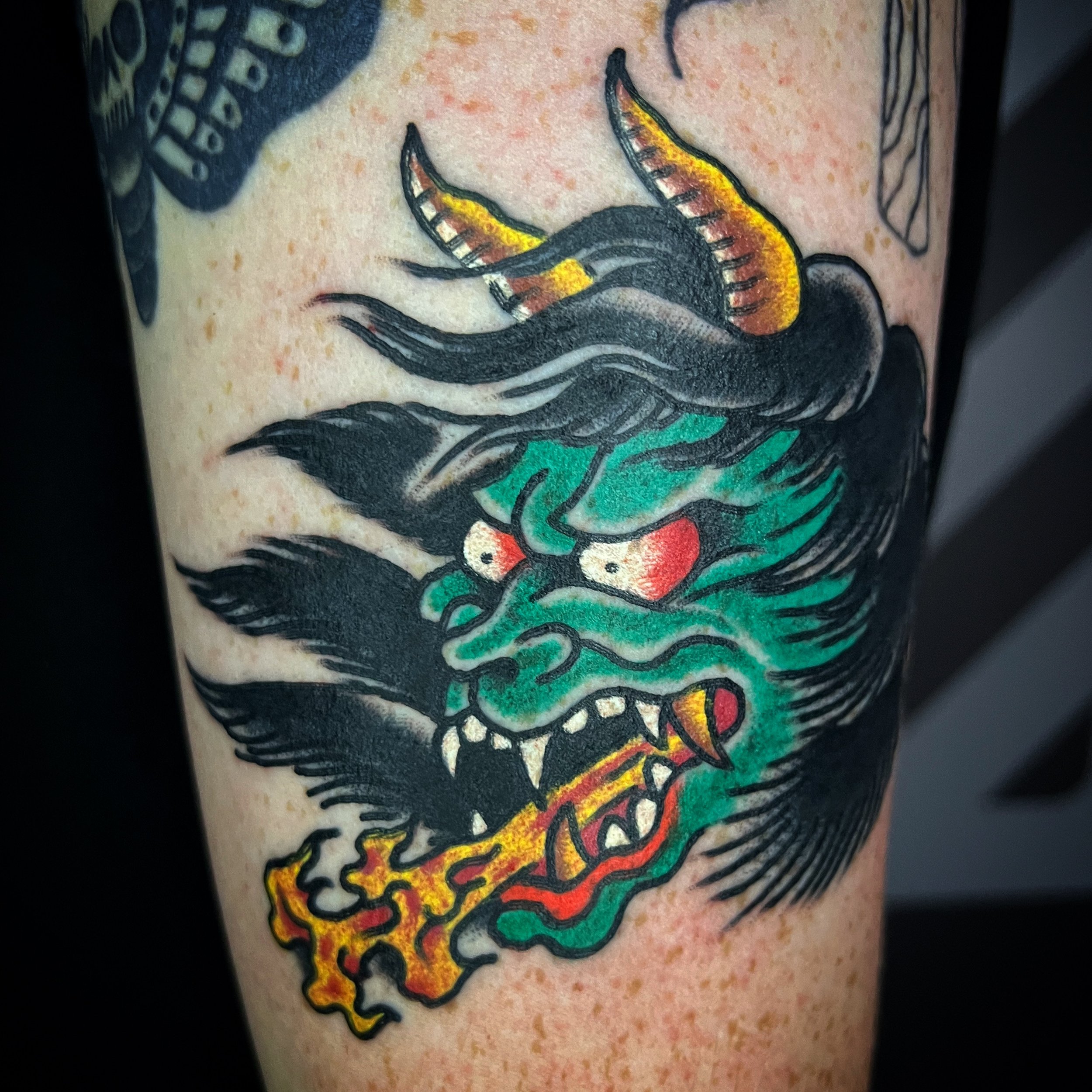 A traditional Japanese style tattoo of a fierce dragon breathing fire.