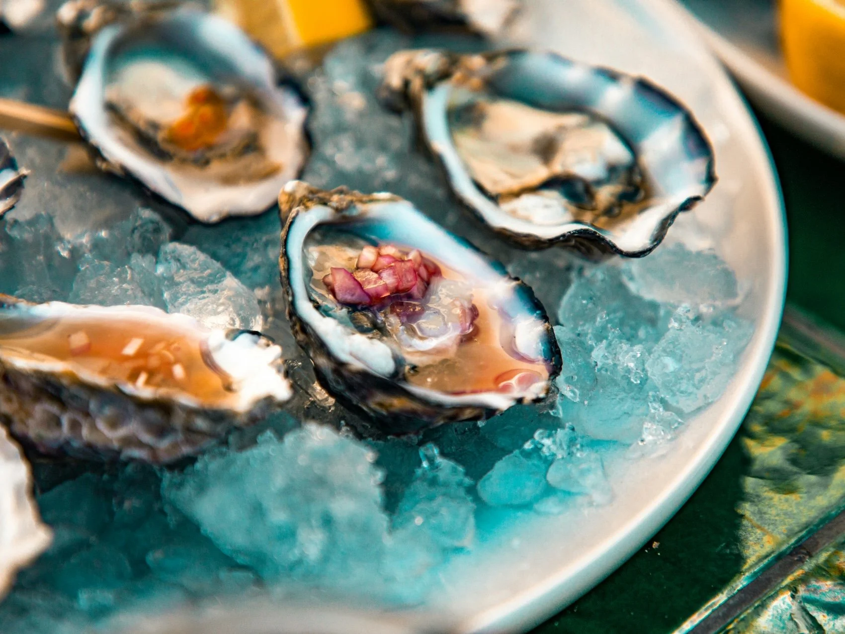 Four fresh oysters on ice with a mignonette sauce.