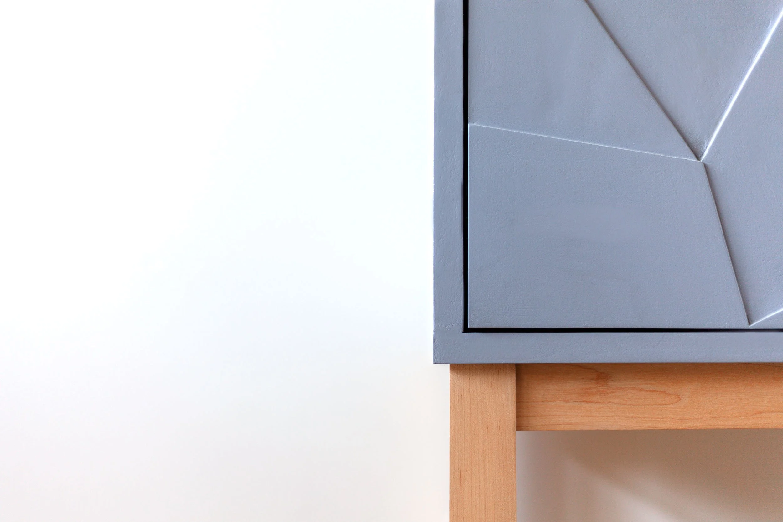 Detail van essenhouten onderstel onder grijze kast van mdf