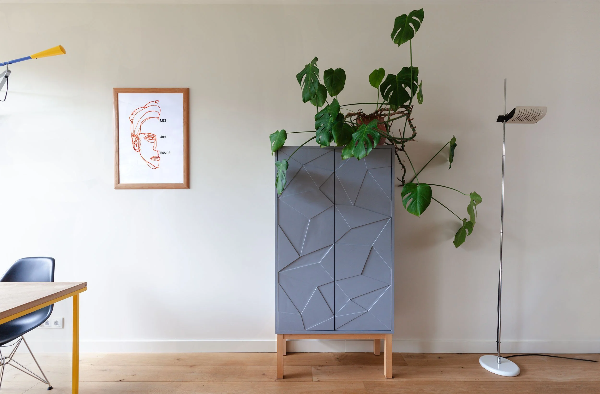 Grijze kast met deuren met geometrische vormen in woonkamer met houten vloer