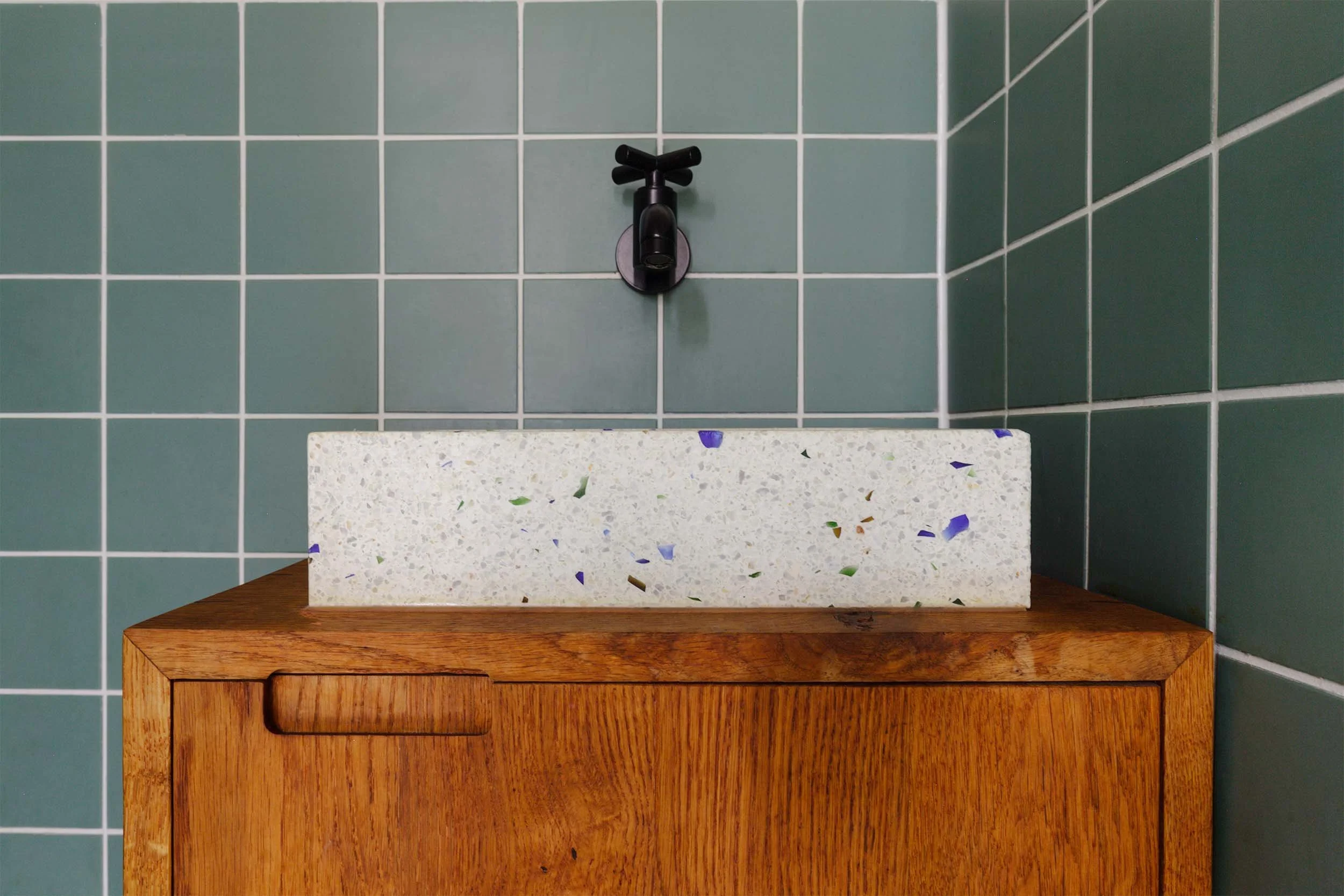 Close-up van toiletmeubel met greep van eikenhout, opbouw wasbak en zwarte tapkraan