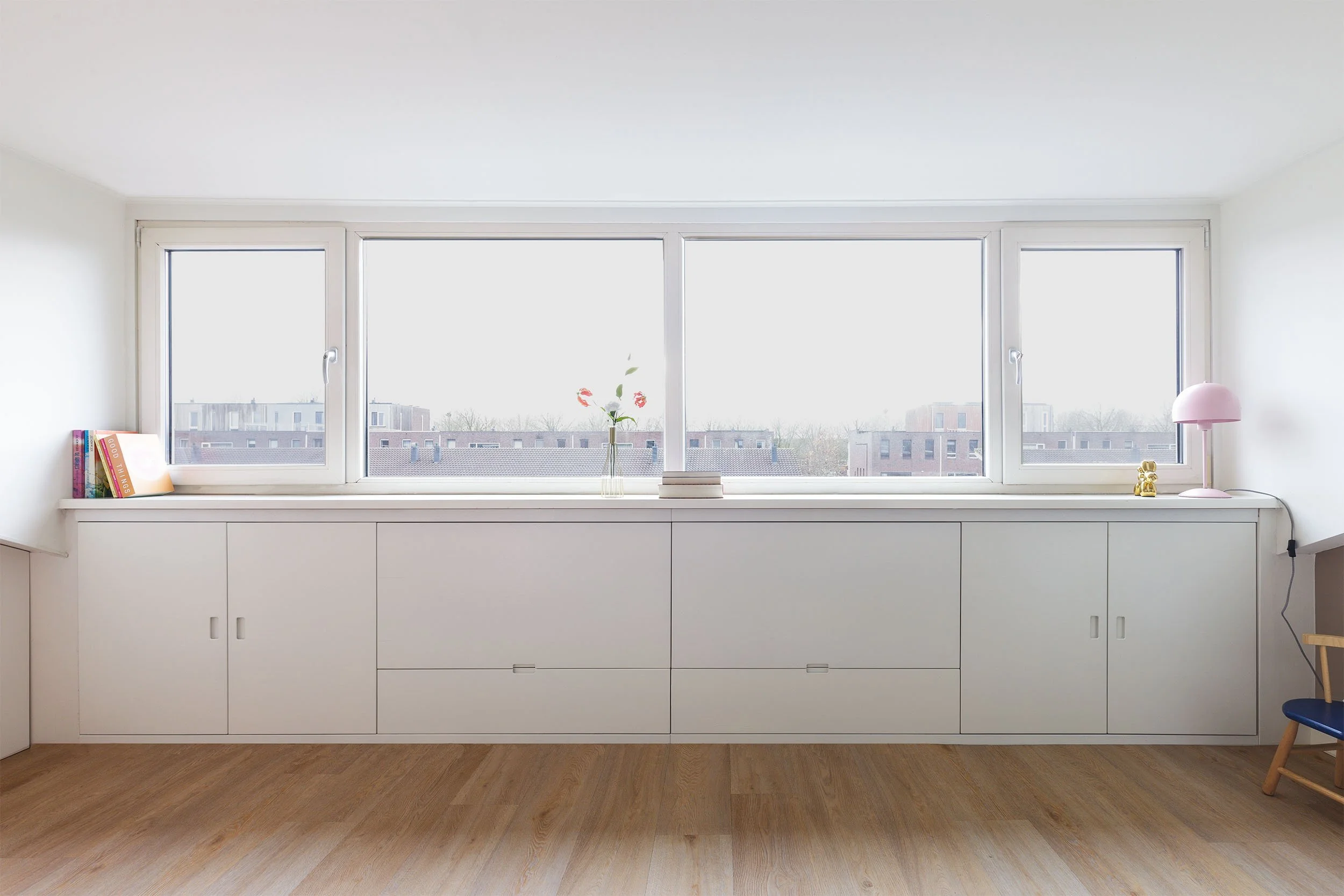 Witte zolderkast onder dakbeschot met laden met ongelijke diepten en deuren