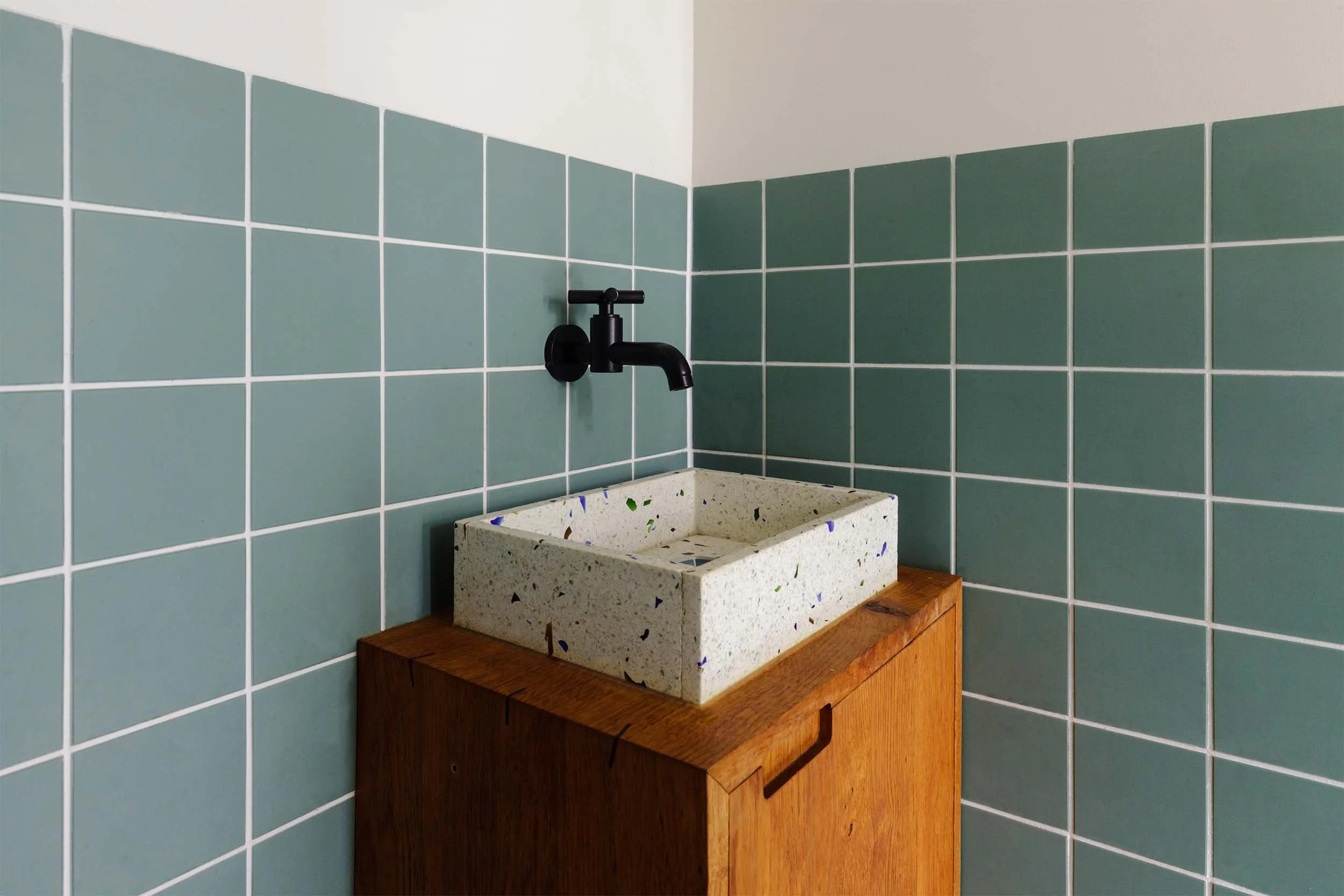 Dornbacht Tara tapkraan boven terrazzo wasbak op meubel in toilet met groene tegels