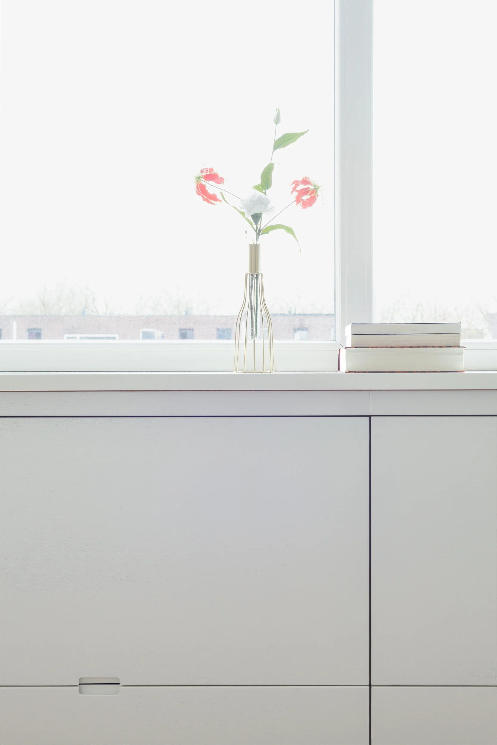 Witte kast op zolder met bloem op vensterbank en boeken