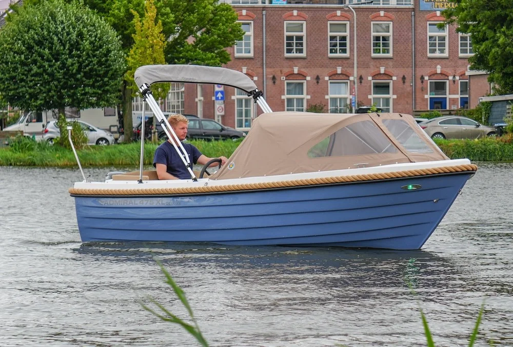 Lichtblauwe Admiral 475 XL sloep met beige kap varend op het water