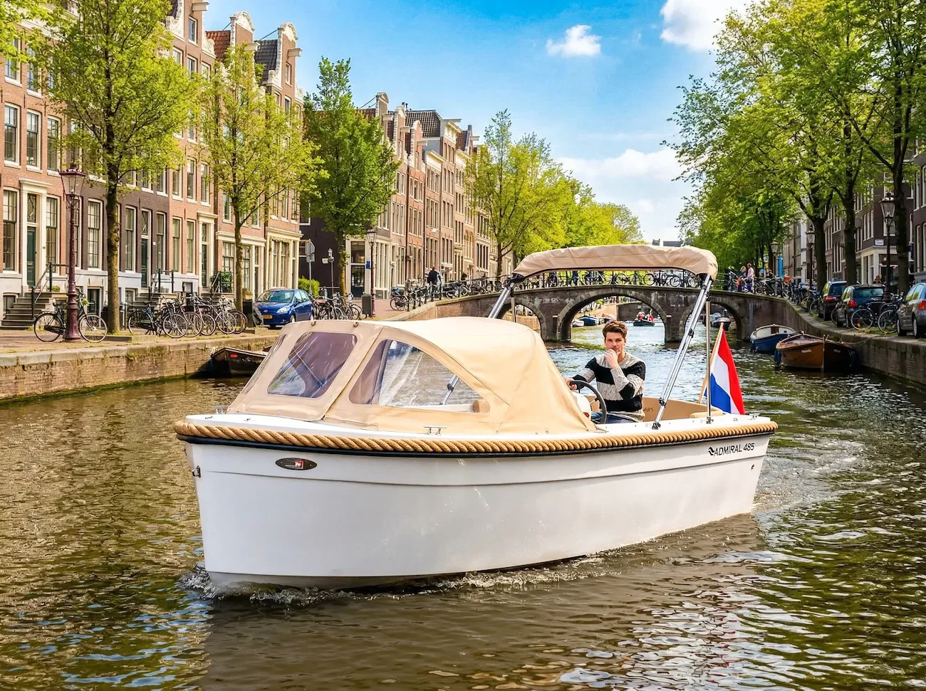 We zeien een witte Admiral 485 sloep luxe moderne boot met beige buiskap en biminitop te koop bij Wormer Watersport, Noord-Holland varend door de grachten van amsterdam.