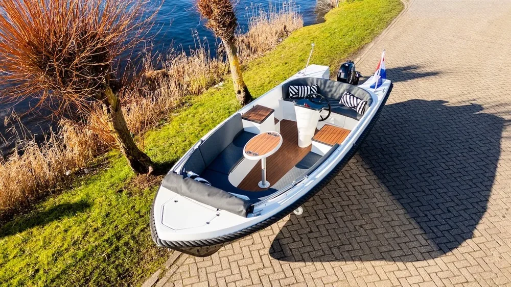 Wit-zwarte Admiral 540 sloep van schuin boven langs het water