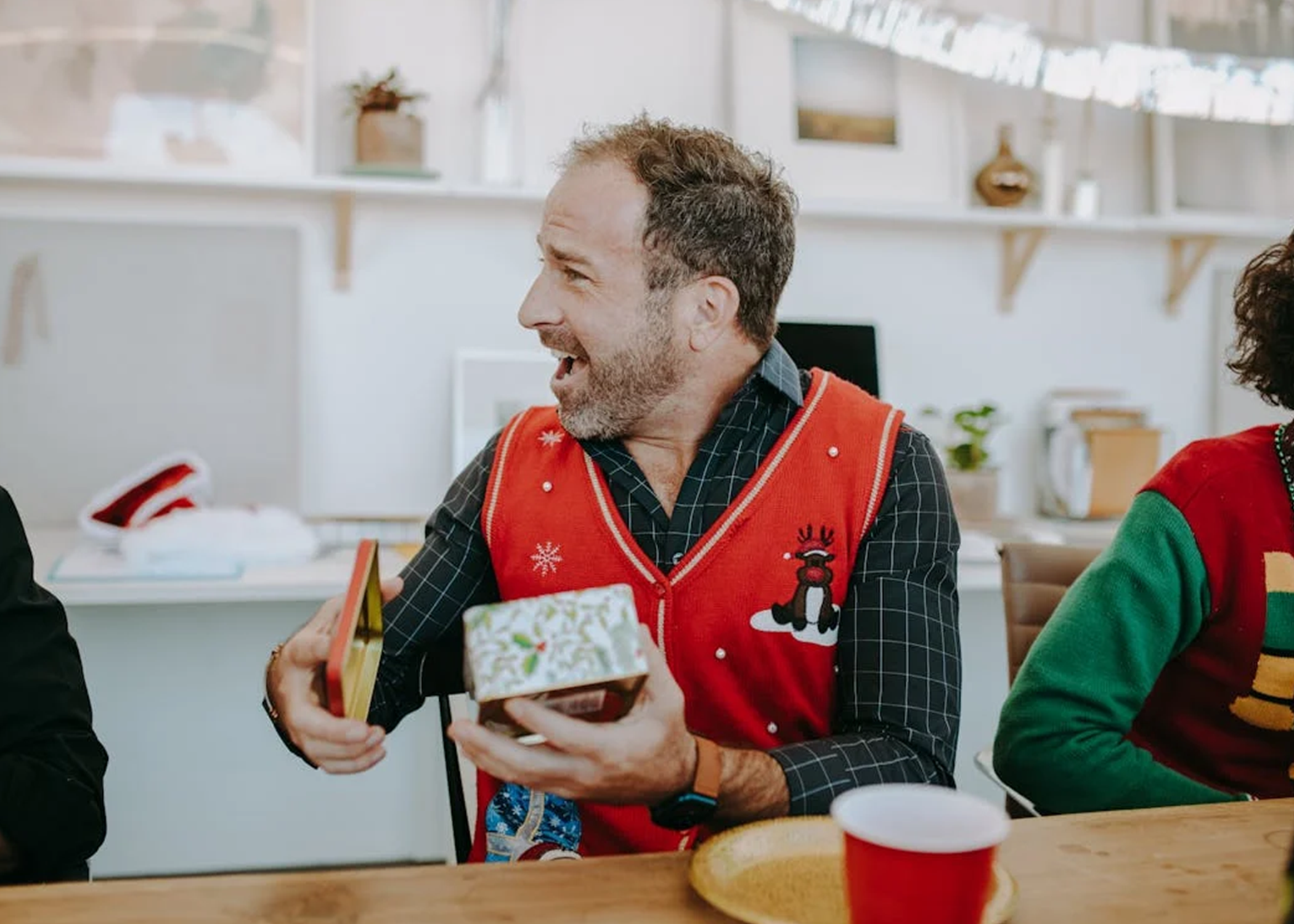 This picture shows a man opening a gift and is shocked at how awesome it is as its from weprintanyhood