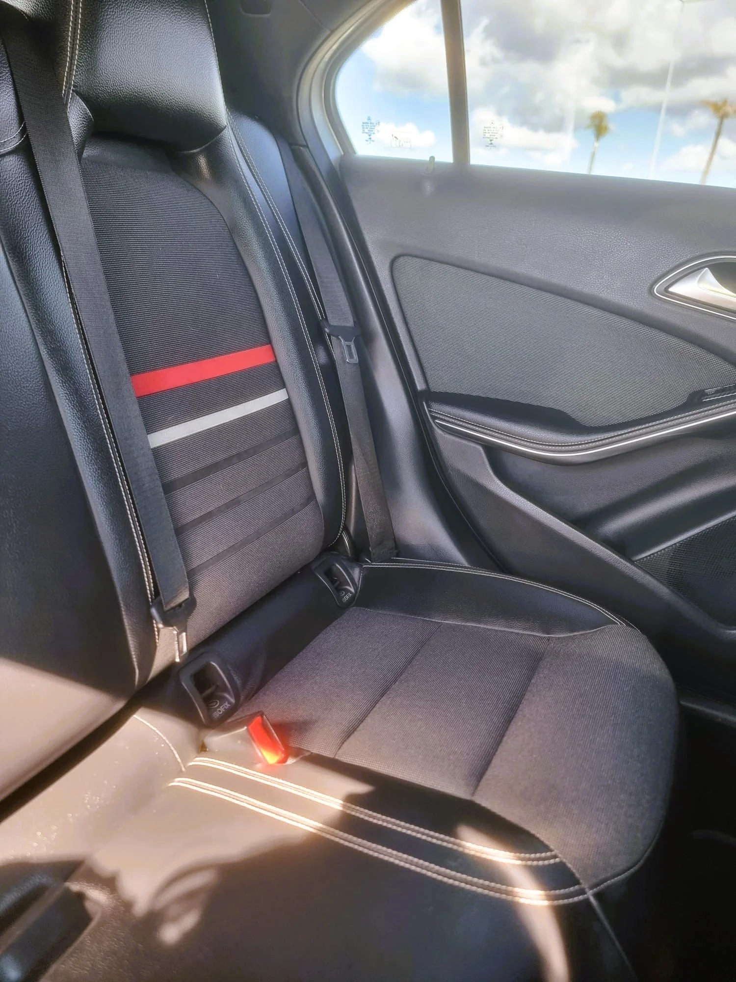 Parte traseira de um carro, mostrando o assento do banco, o cinto de segurança e a porta.