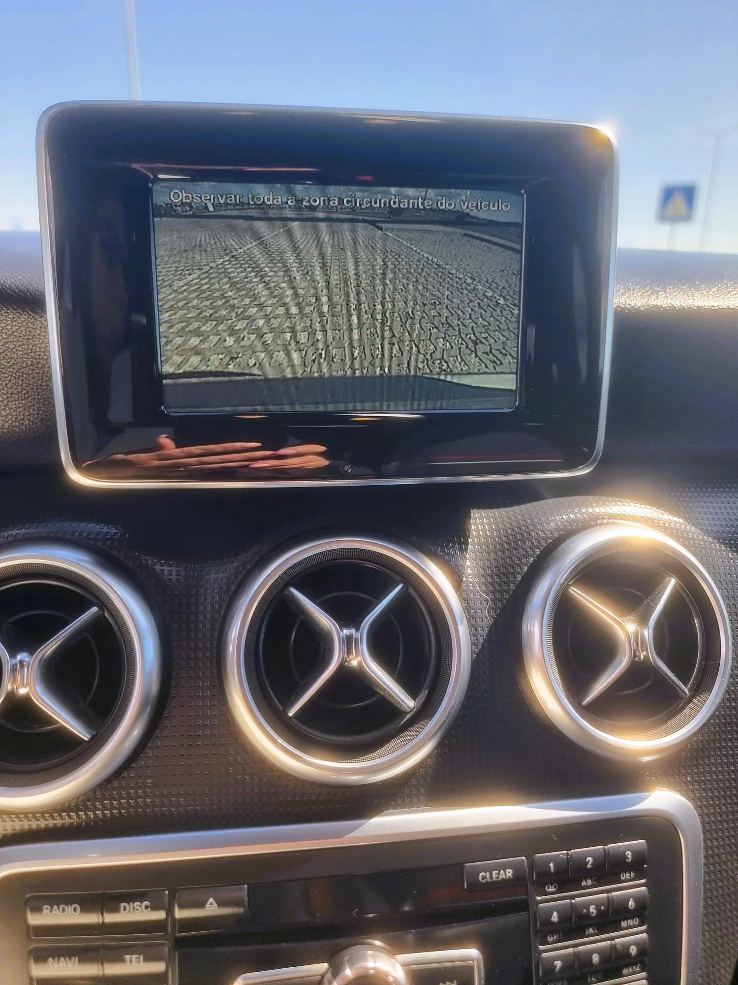 Tela do sistema de câmeras do carro exibindo uma visão da área ao redor do veículo, com a mensagem 'Observar toda a zona circundante do veículo'.