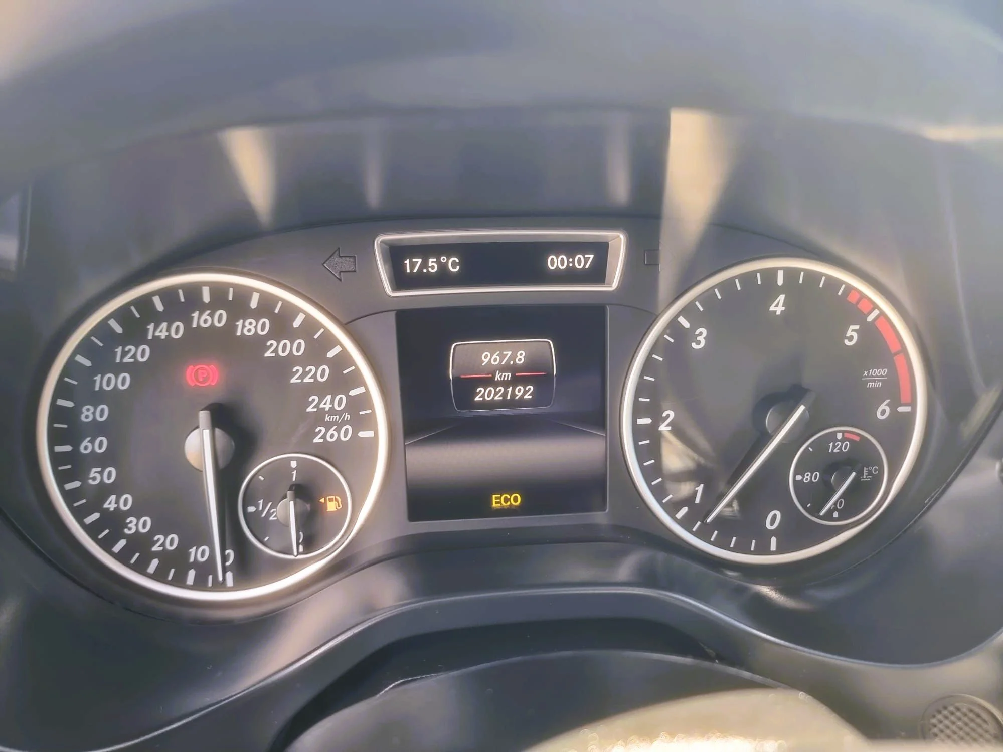 Painel do carro mostrando velocidade de 0 km/h, temperatura externa de 17.5°C, odômetro de 202192 km, consumo de combustível, luz de freio acesa, marcador de RPM, temperatura do motor, e indicador de modo ECO.