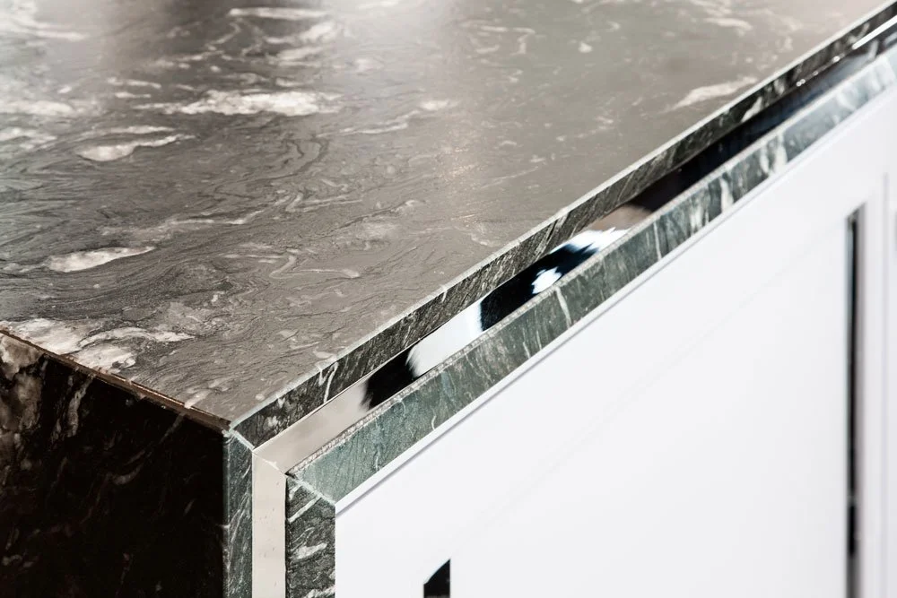 Close-up of a black and white marble countertop with a glossy finish, mounted on a white cabinet.