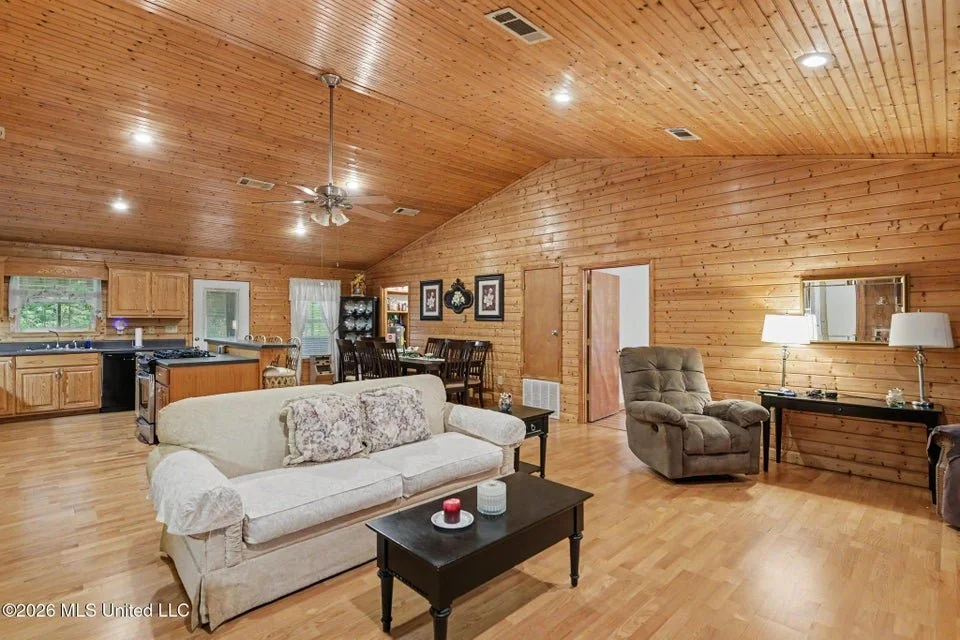 Home for sale in Lucedale. Home for sale in George County. Home on the river in Lucedale with a raised porch and stairs, surrounded by a grassy yard and trees, with a small shed on the left and bird feeders hanging from trees.