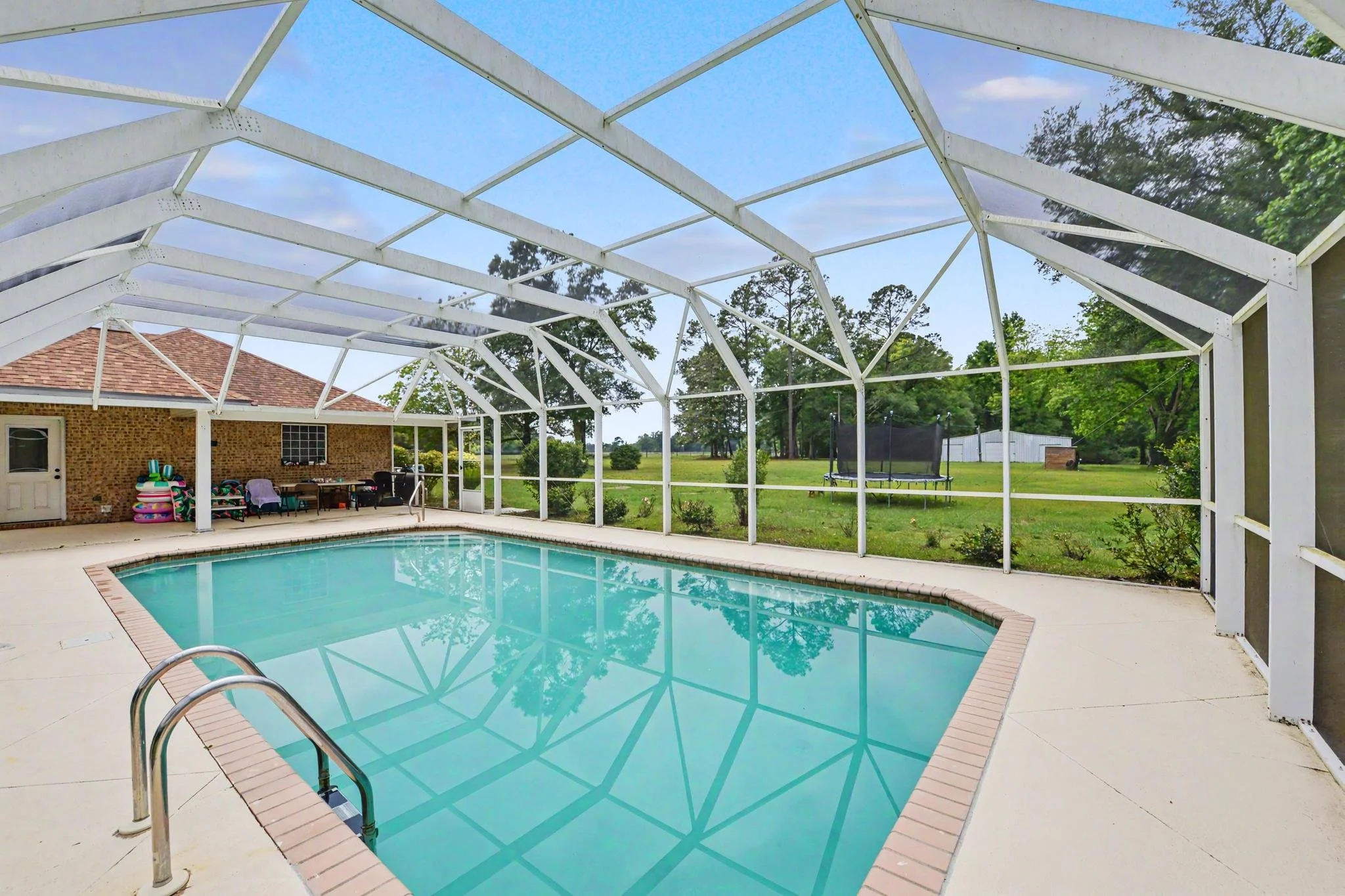 home located in lucedale, ms with 4 acres and three bedrooms and two baths with an enclosed pool cover over the in-ground pool with a workshop