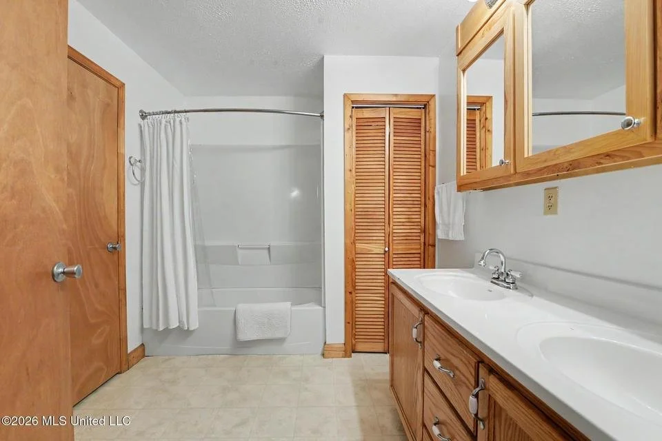 Home for sale in Lucedale. Home for sale in George County. Home on the river in Lucedale with a raised porch and stairs, surrounded by a grassy yard and trees, with a small shed on the left and bird feeders hanging from trees.