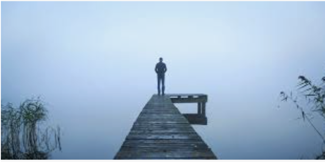 Man standing alone on foggy pier contemplating | depression treatment for young men in Arlington, Virginia