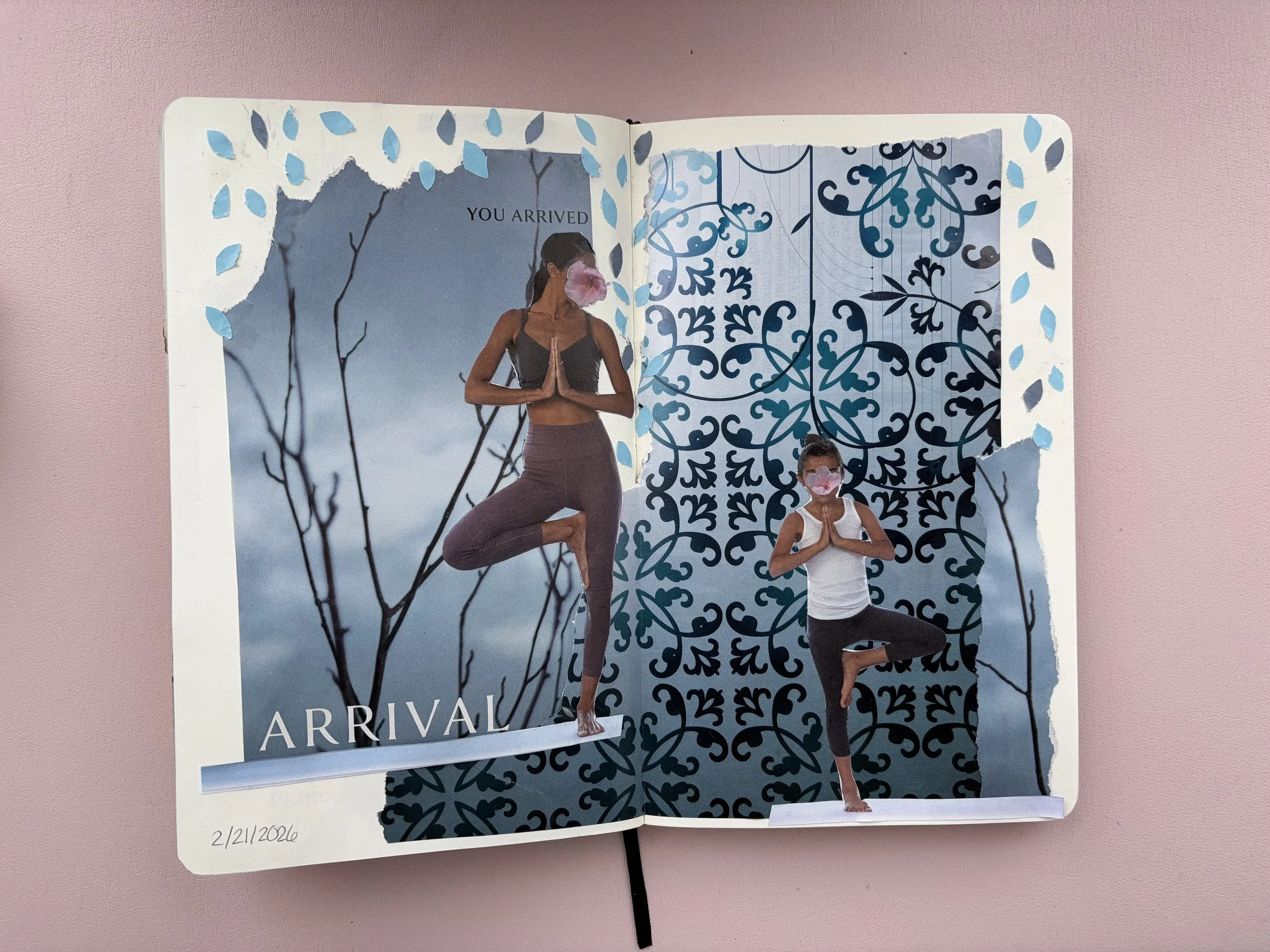 A scrapbook or journal page with collage art featuring two women in yoga poses, one larger and one smaller, with masks or faces obscured by pink flowers. The background has sky and tree motifs, and the words 'YOU ARRIVED' and 'ARRIVAL' are printed on