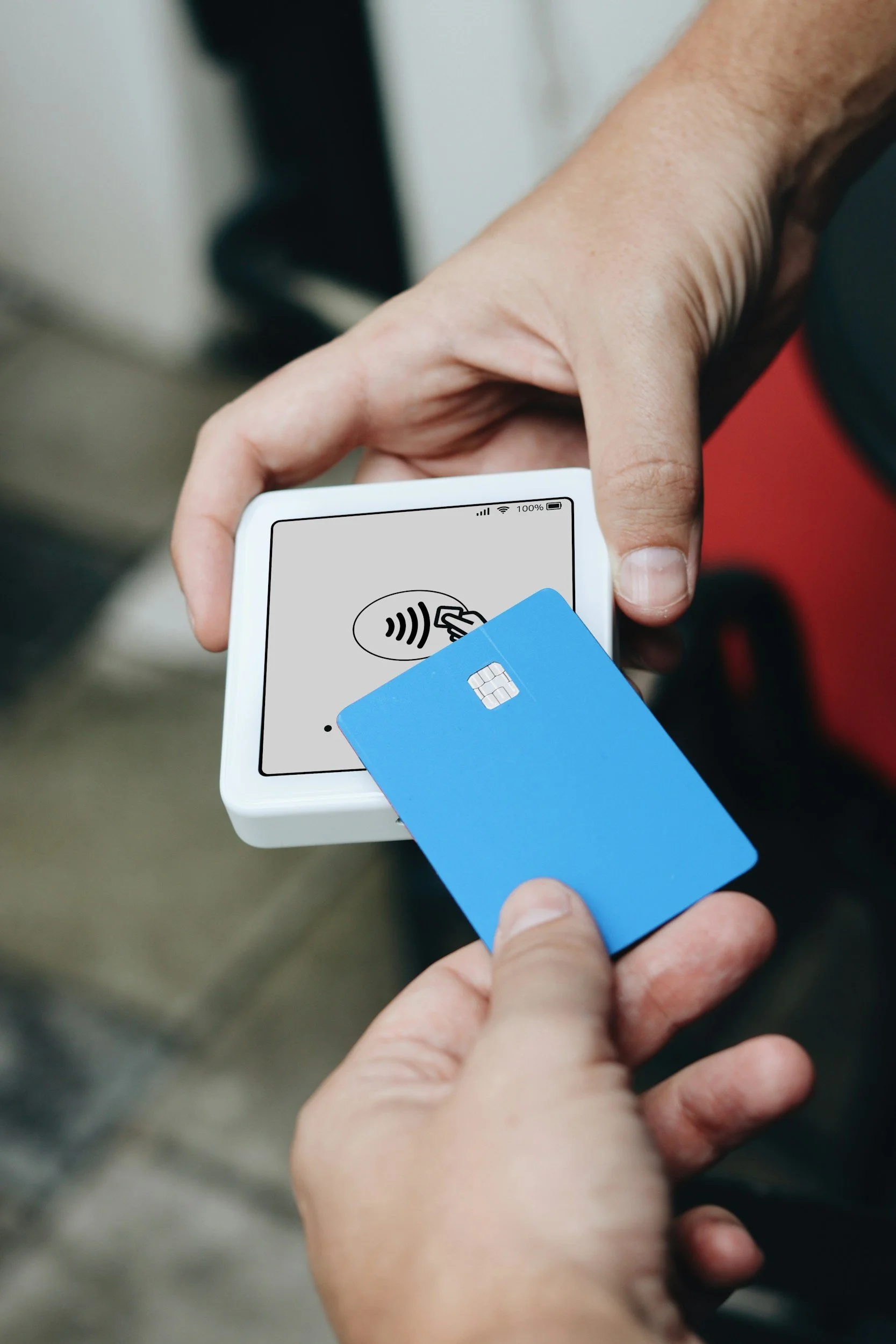 Person holding a contactless payment terminal while about to scan a blue access card.