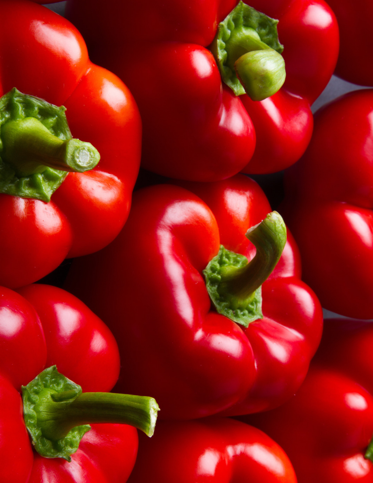 Grupo de pimientos rojos con tallo verde.