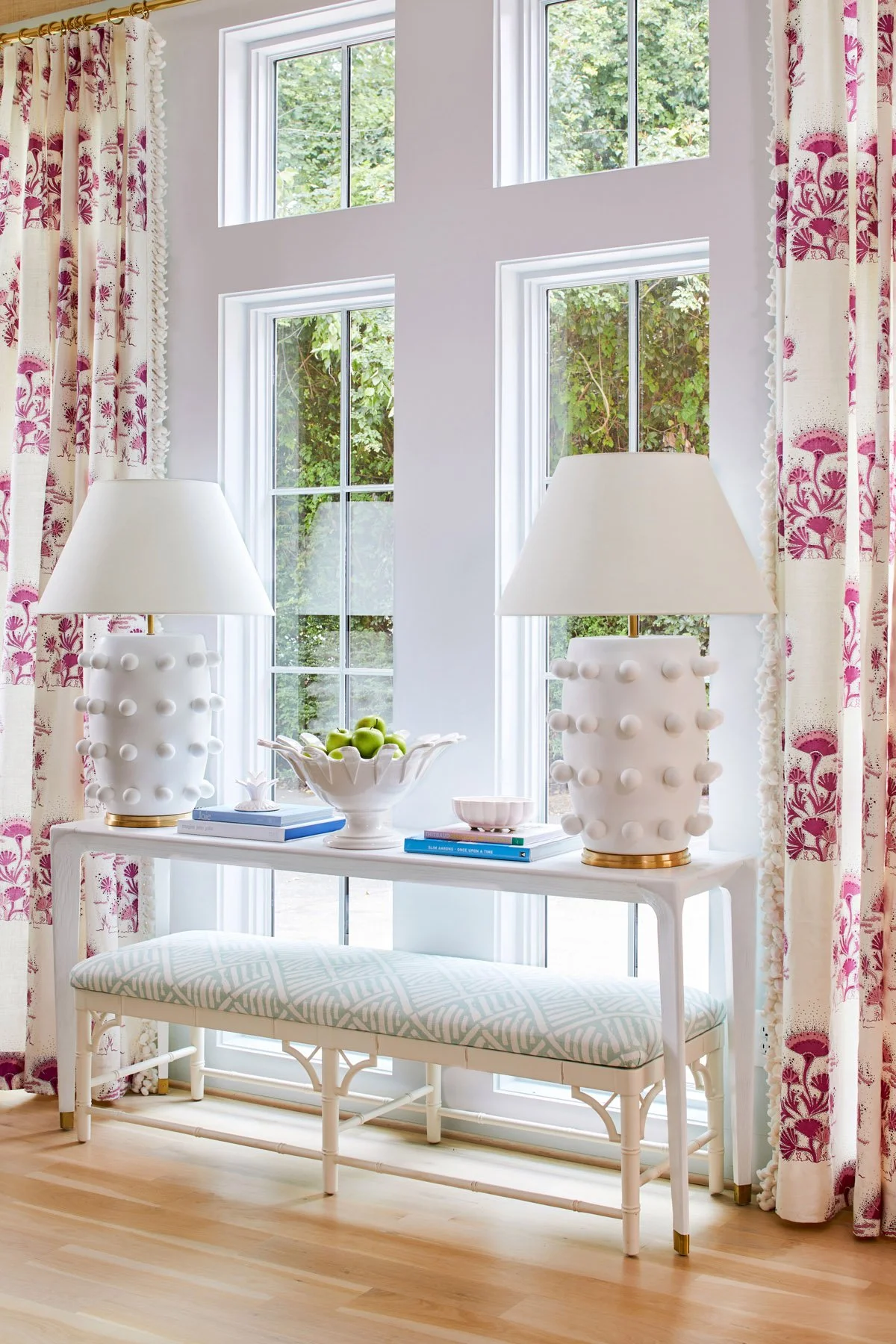 A vingette of a console table styled with two large white lamps and blue coffee table books styled by lindsey ellis beatty