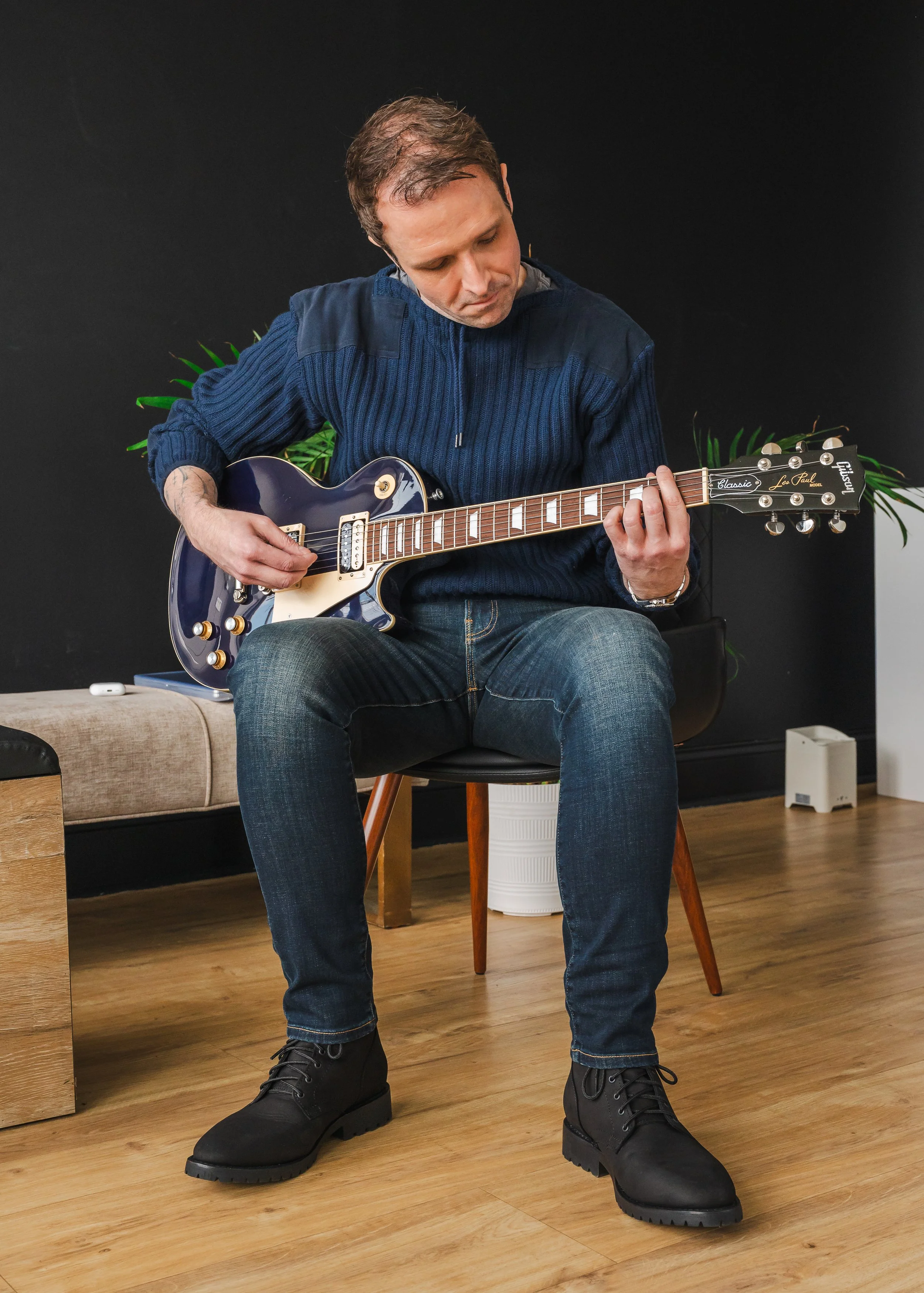 A branding portrait of a professional working remotely and taking a break to play a song on his guitar