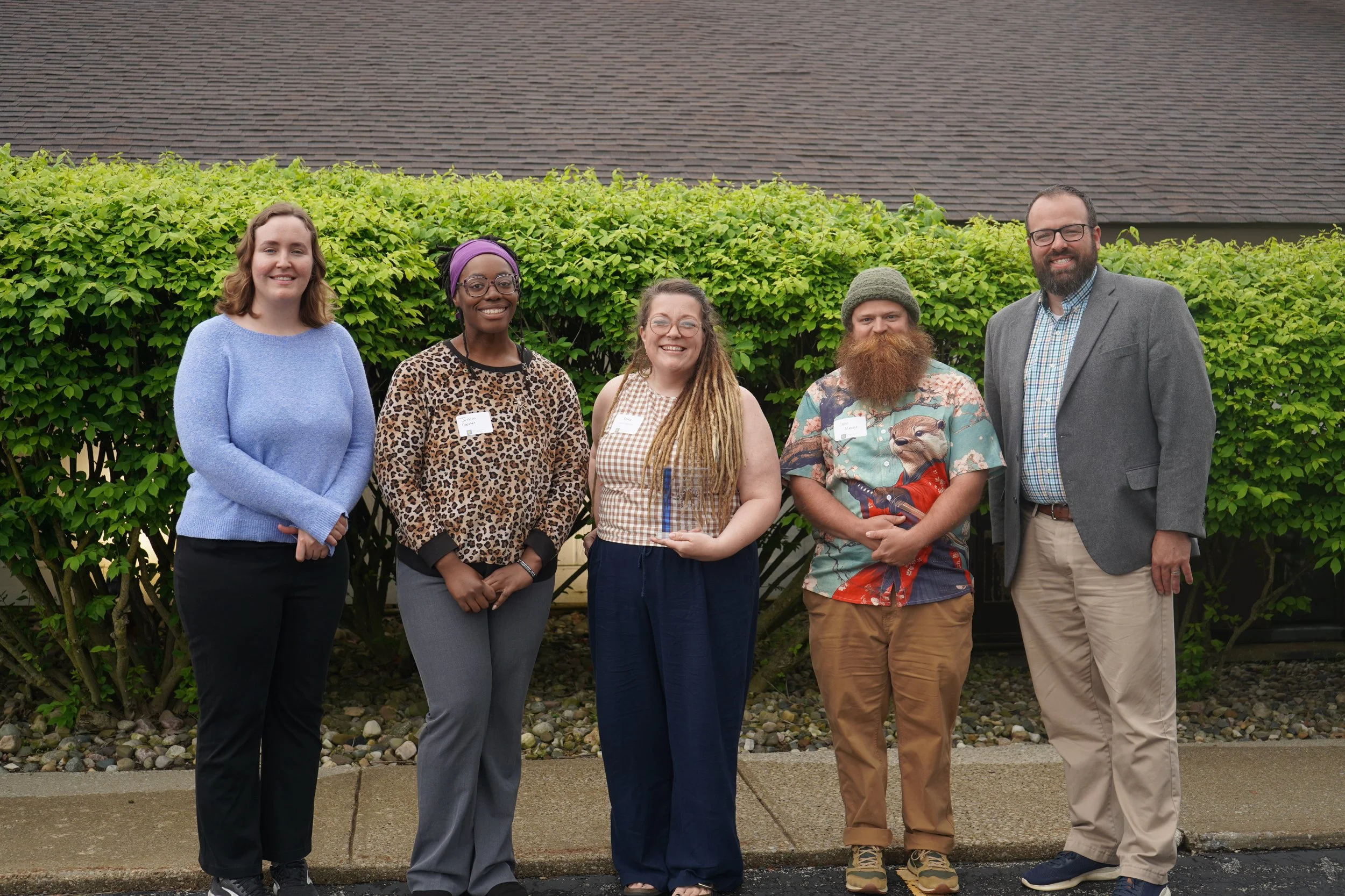 Five people standing with the middle person holding the award.