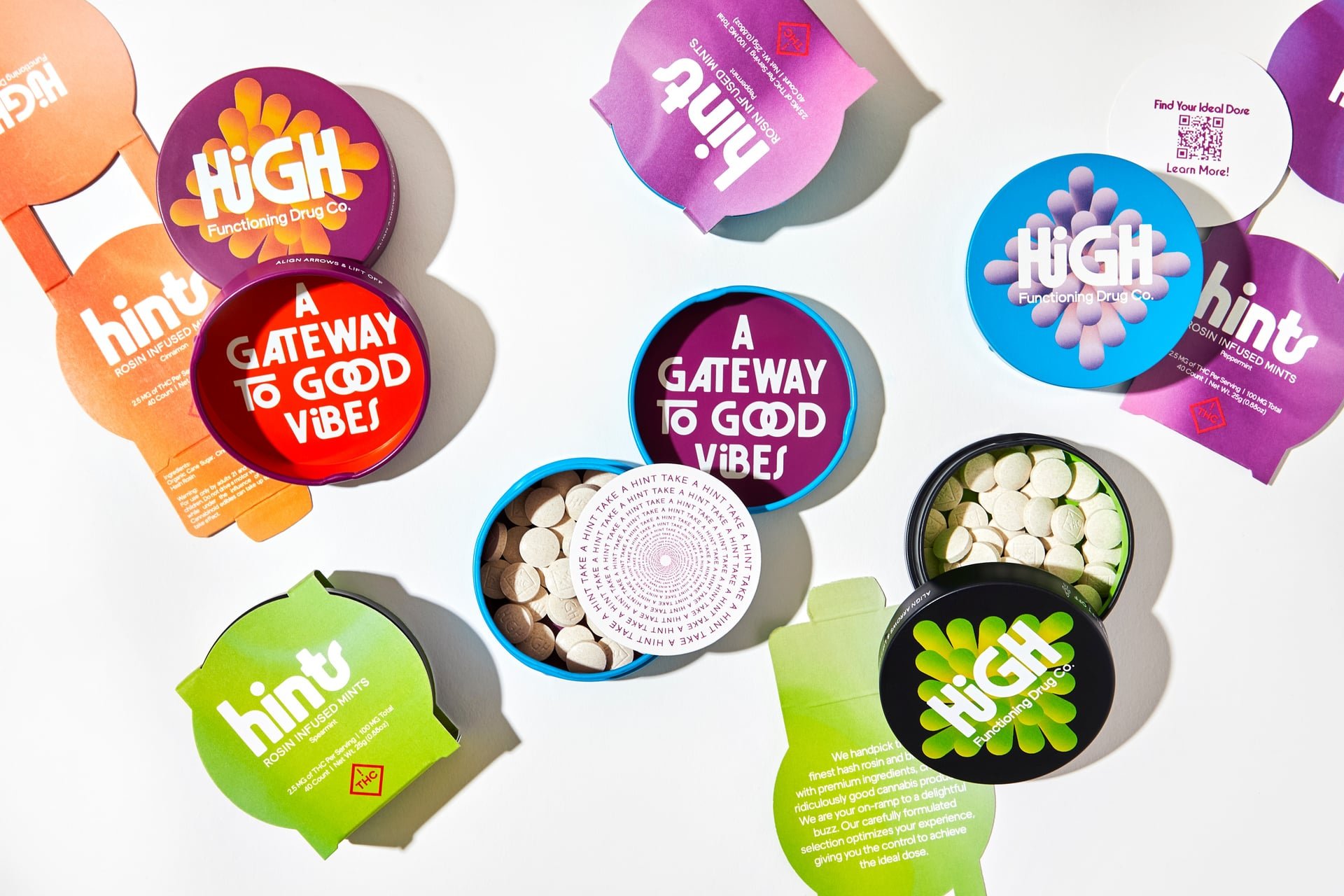 Various flavored tins of Hint's low dose cannabis-infused mints, with labels reading 'A Gateway to Good Vibes,' 'high,' and 'Hint,'.