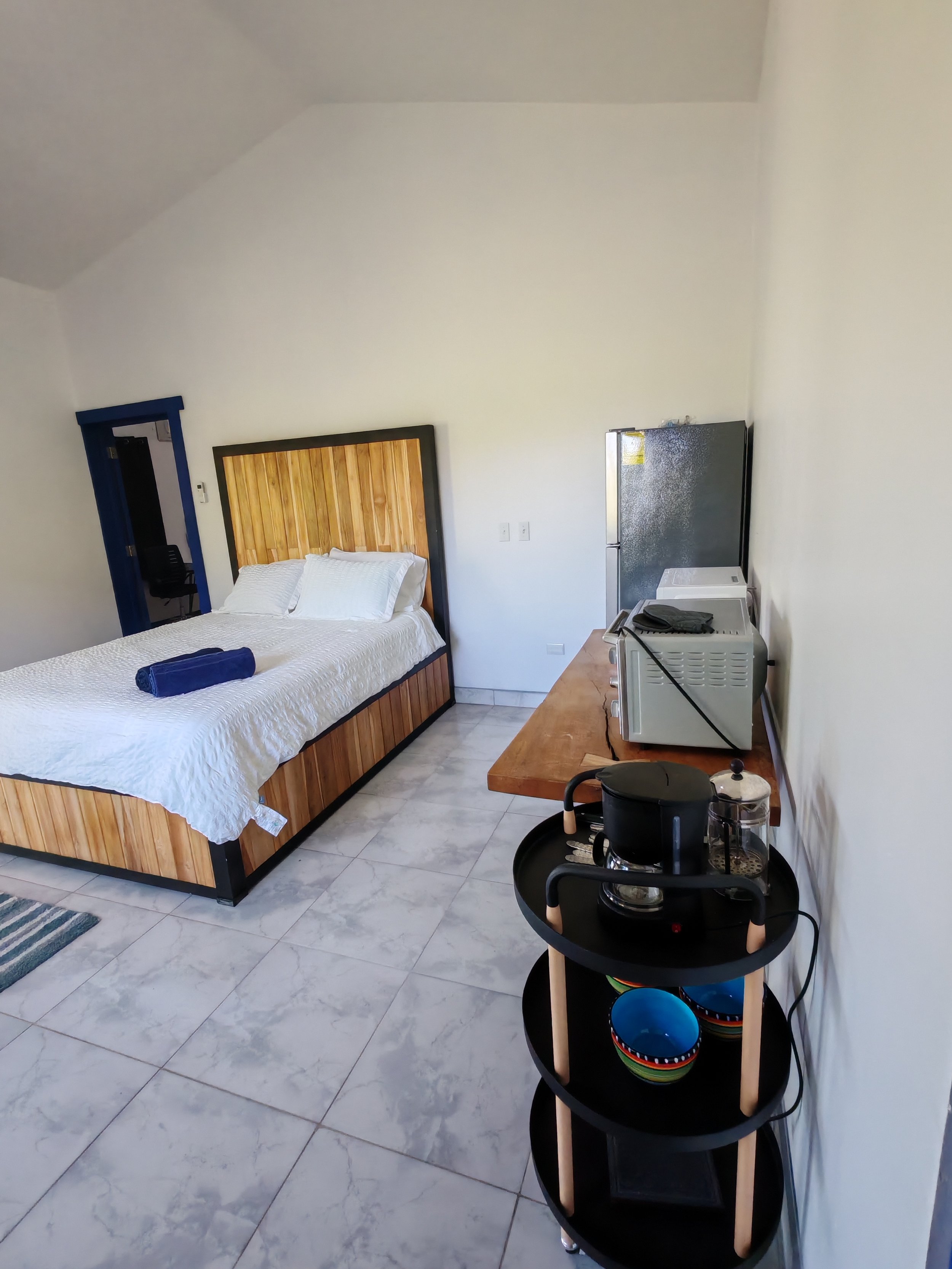 Queen bed, coffee pot, toaster oven and fridge