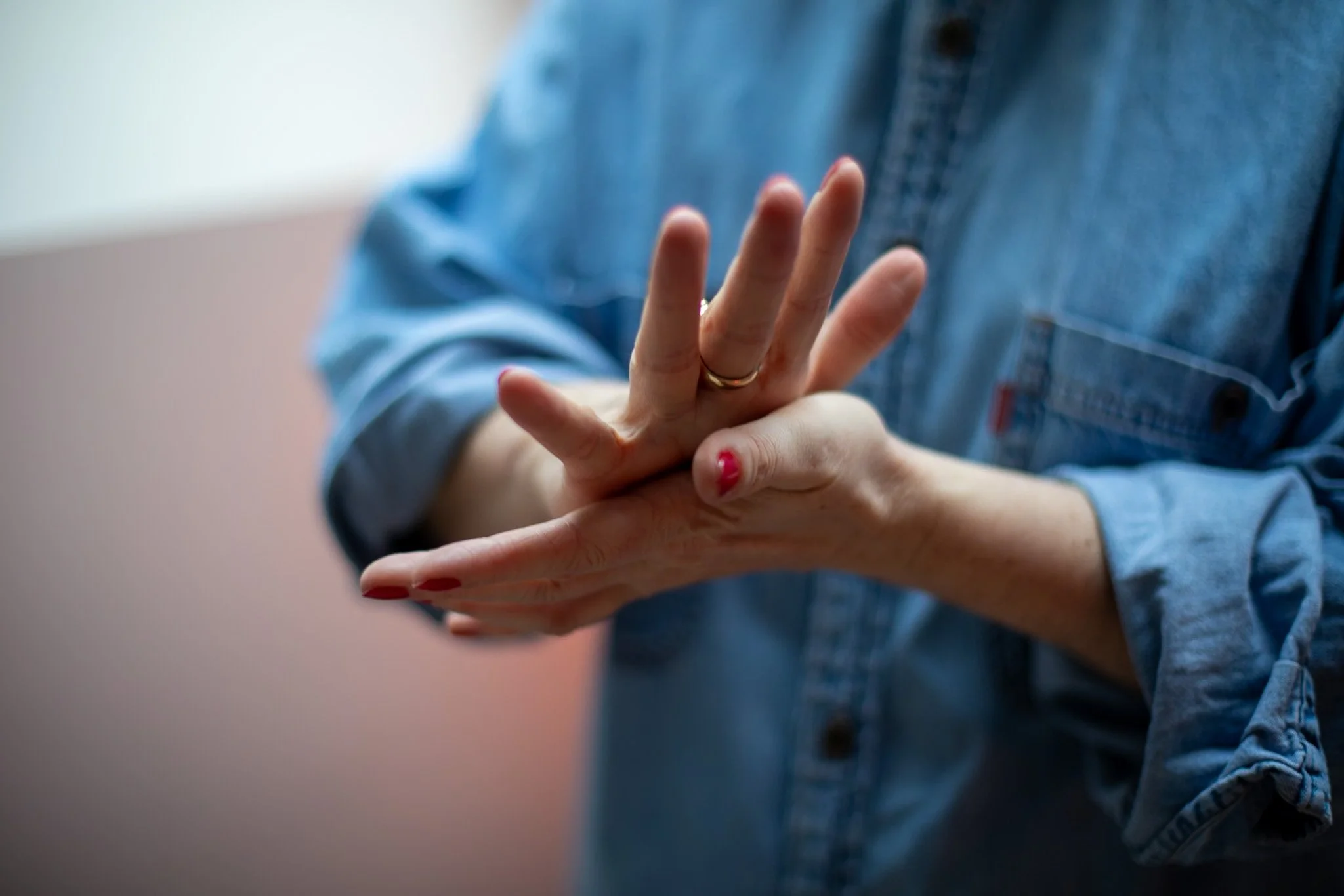 Close-up of a person adjusting their wrist with a casual blue denim shirt, showing finger and hand details.
