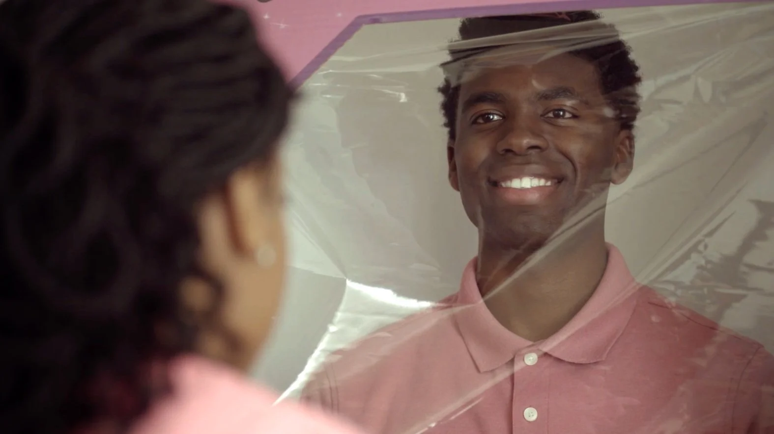 Person smiling behind a clear plastic barrier