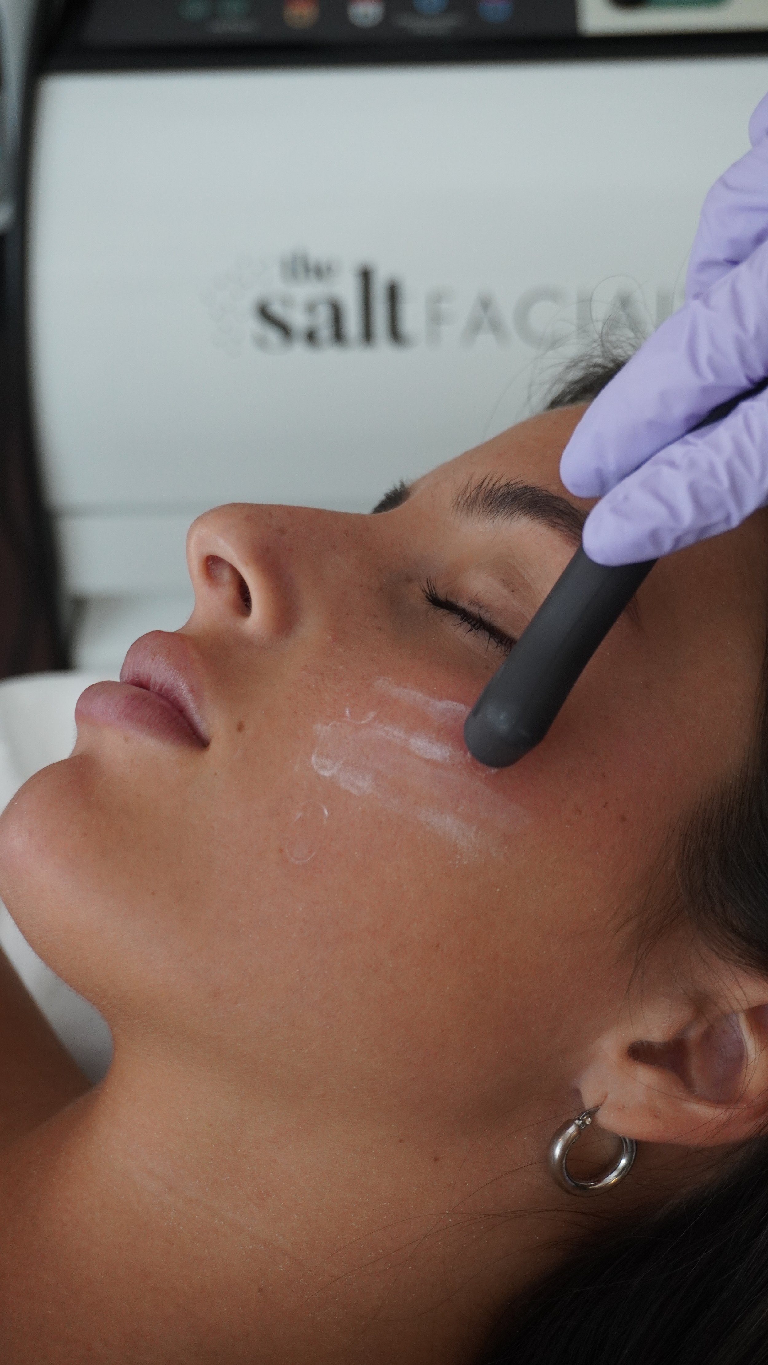A person receiving a facial treatment with a handheld device at a skincare clinic.