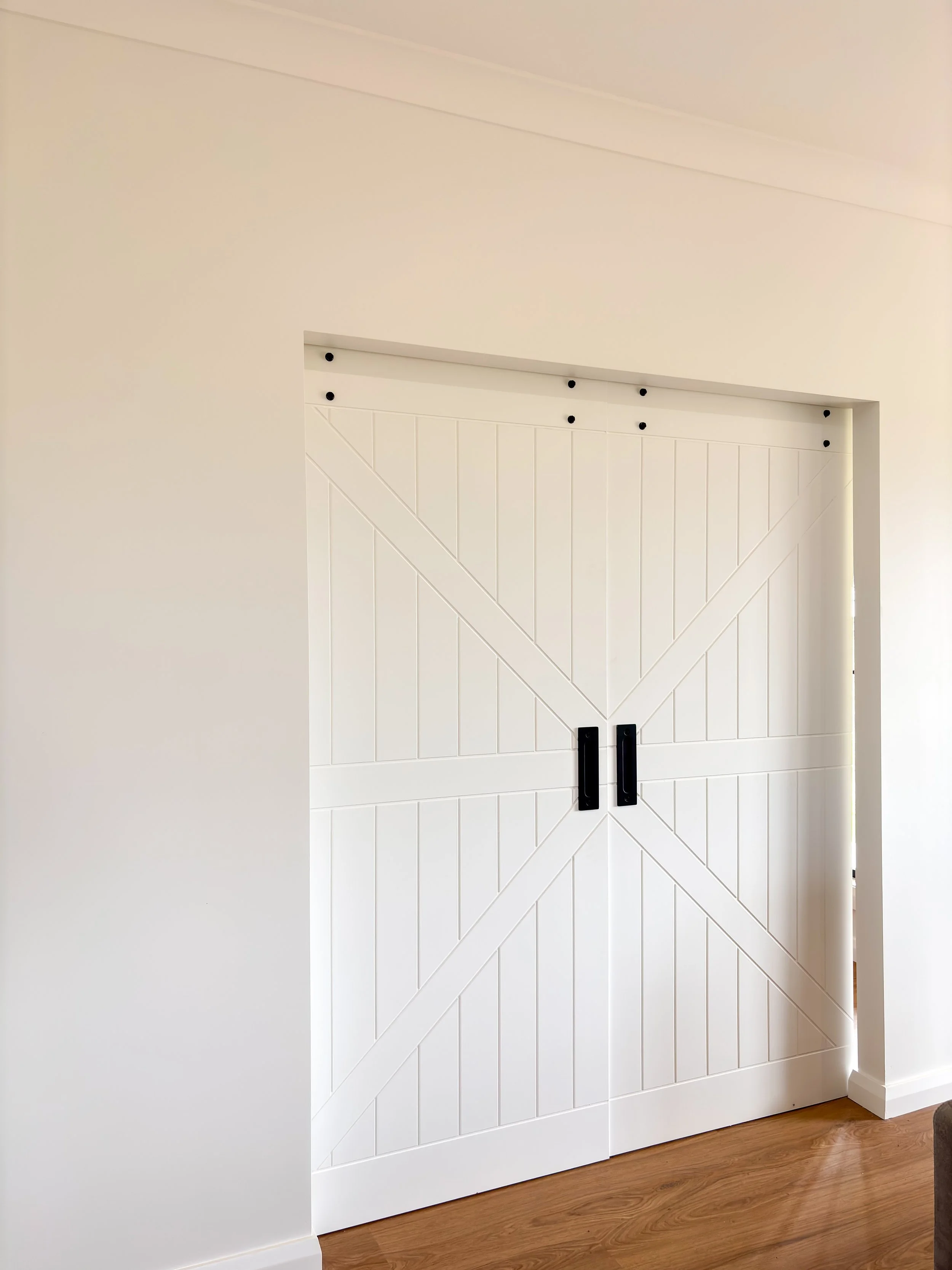 White sliding barn door custom build with black hardware on a wall by Whitbuild, Forbes NSW