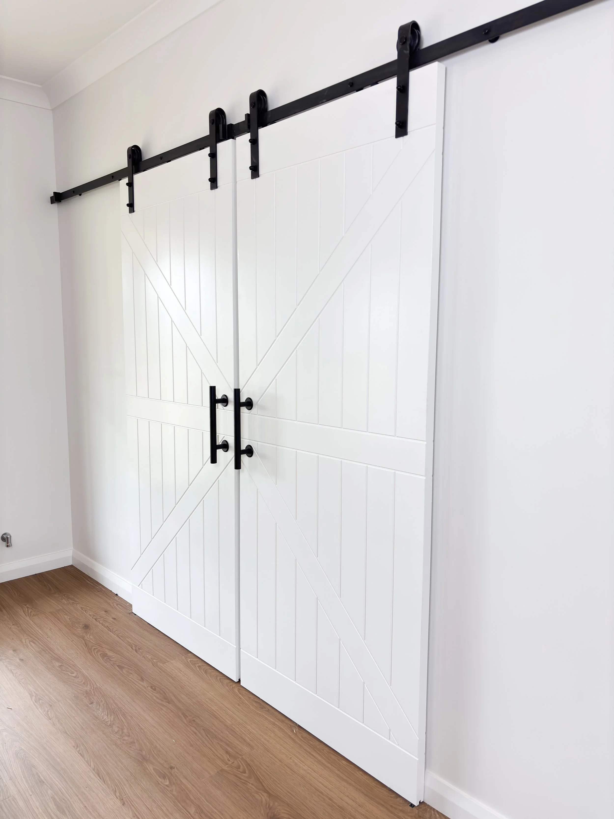 White sliding barn door custom build with black hardware on a wall by Whitbuild, Forbes NSW