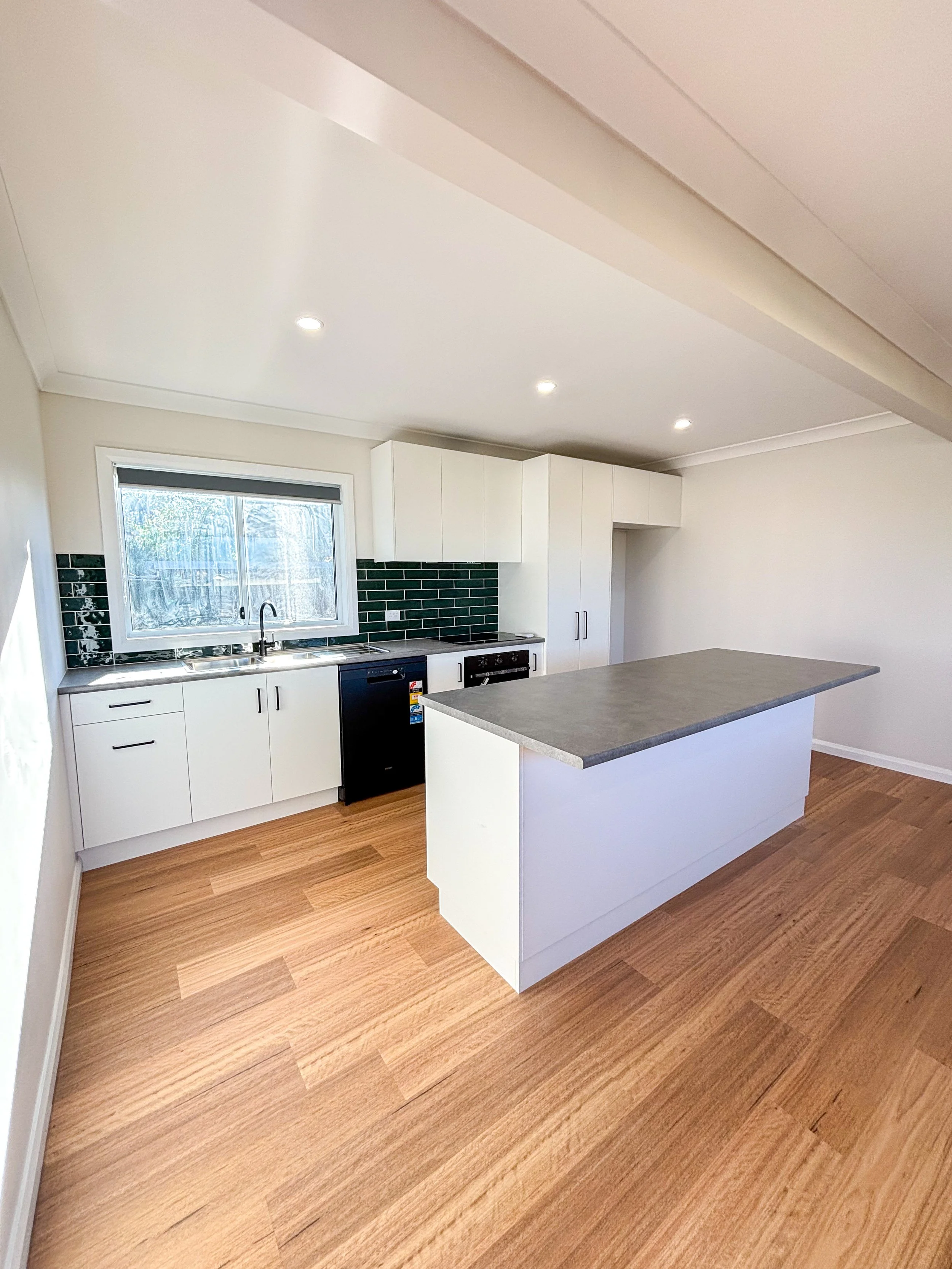 Modern kitchen renovation with white cabinets, black appliances, wood flooring, that made it  bright, functional and built to suit modern family living by Whitbuild, Cowra NSW