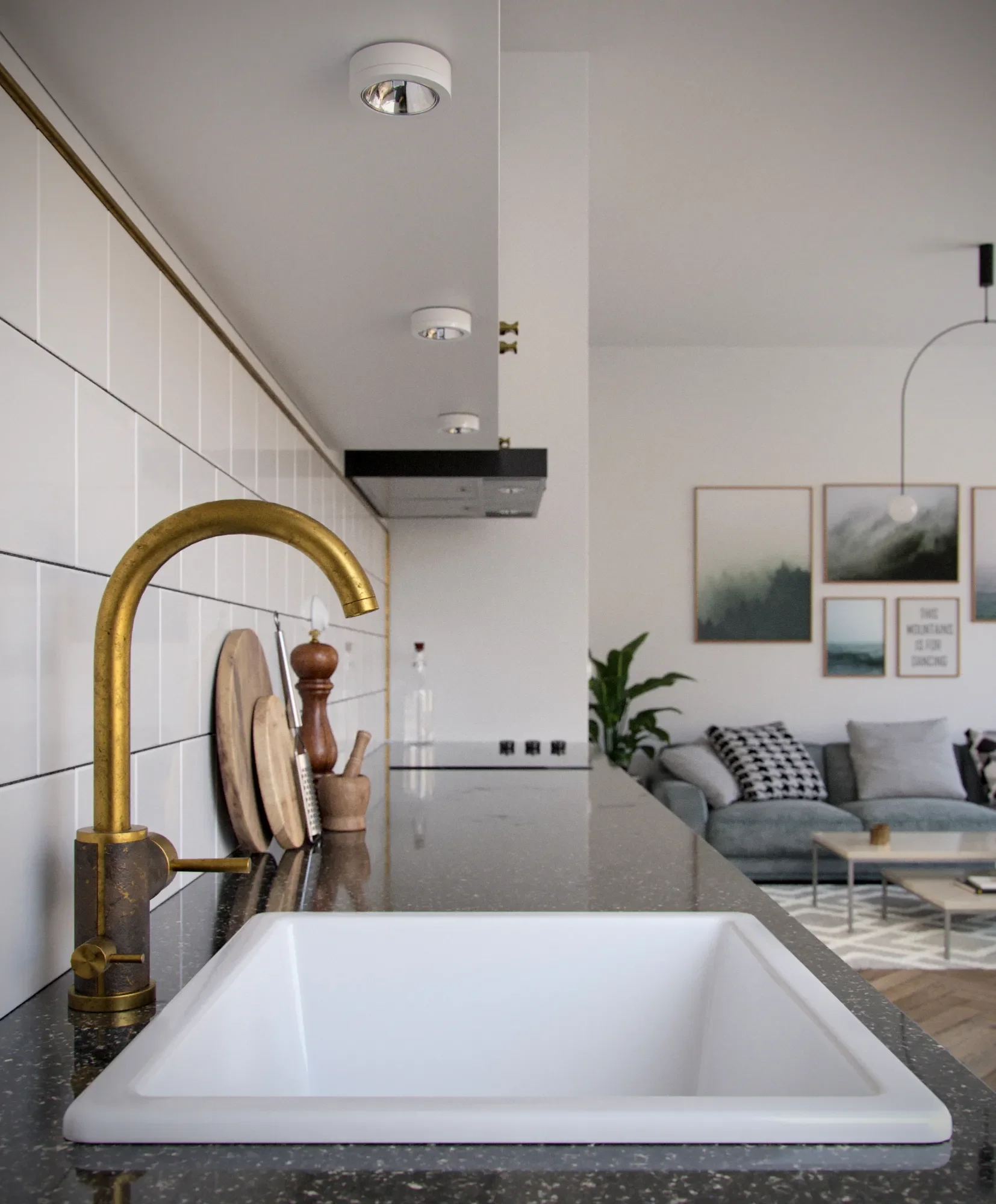 Modern kitchen with white tiled wall, black countertop, brass faucet, and a white sink.