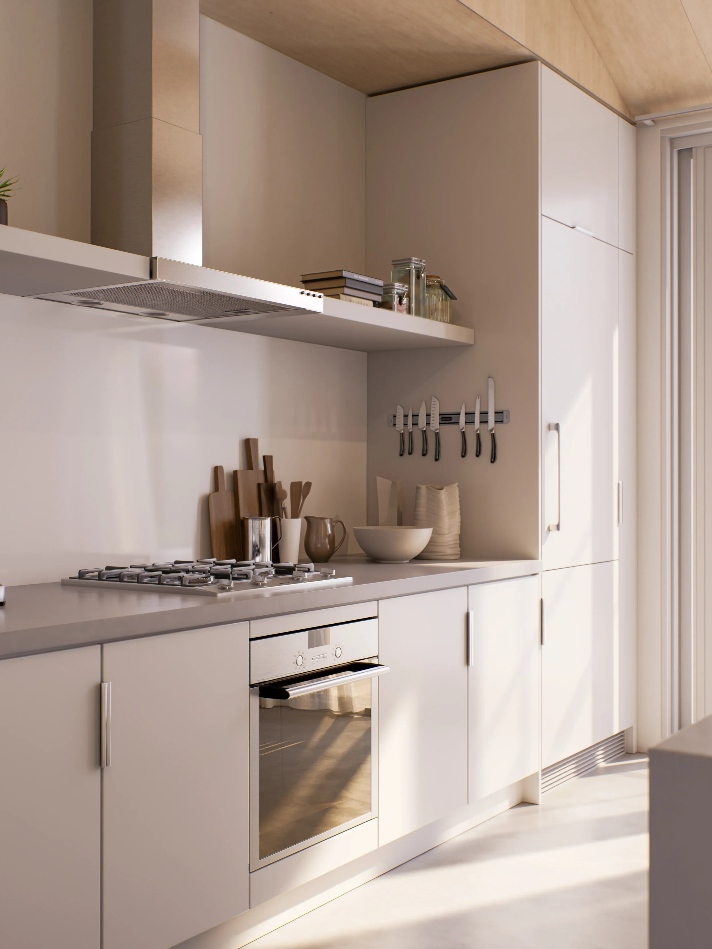 Minimalist cream-colored kitchen with cabinets, stovetop, oven, and open shelves holding books and jars, illuminated by natural light.