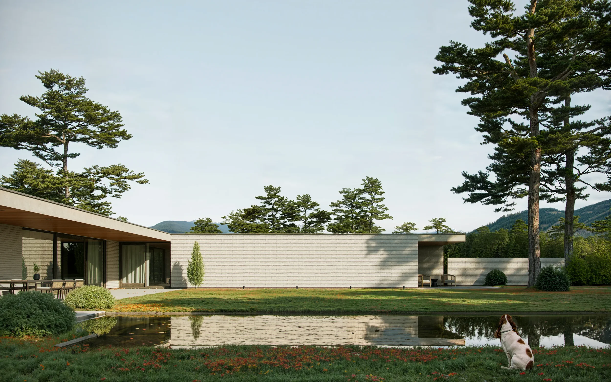 Modern house with large windows in a peaceful yard, tall pine trees, a pond, and a dog sitting near the water, mountains in the background.