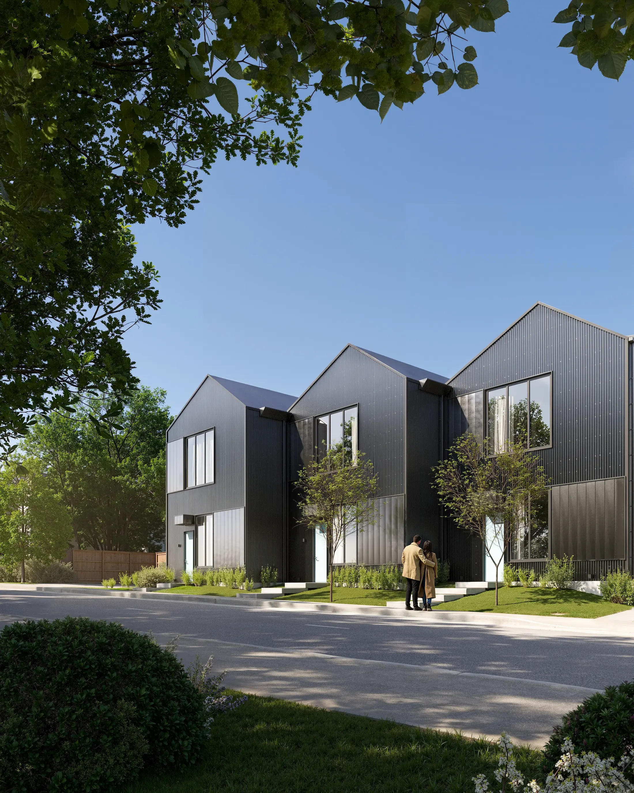 Modern black townhouse with three sections, large windows, small front yard, and two people walking on sidewalk.