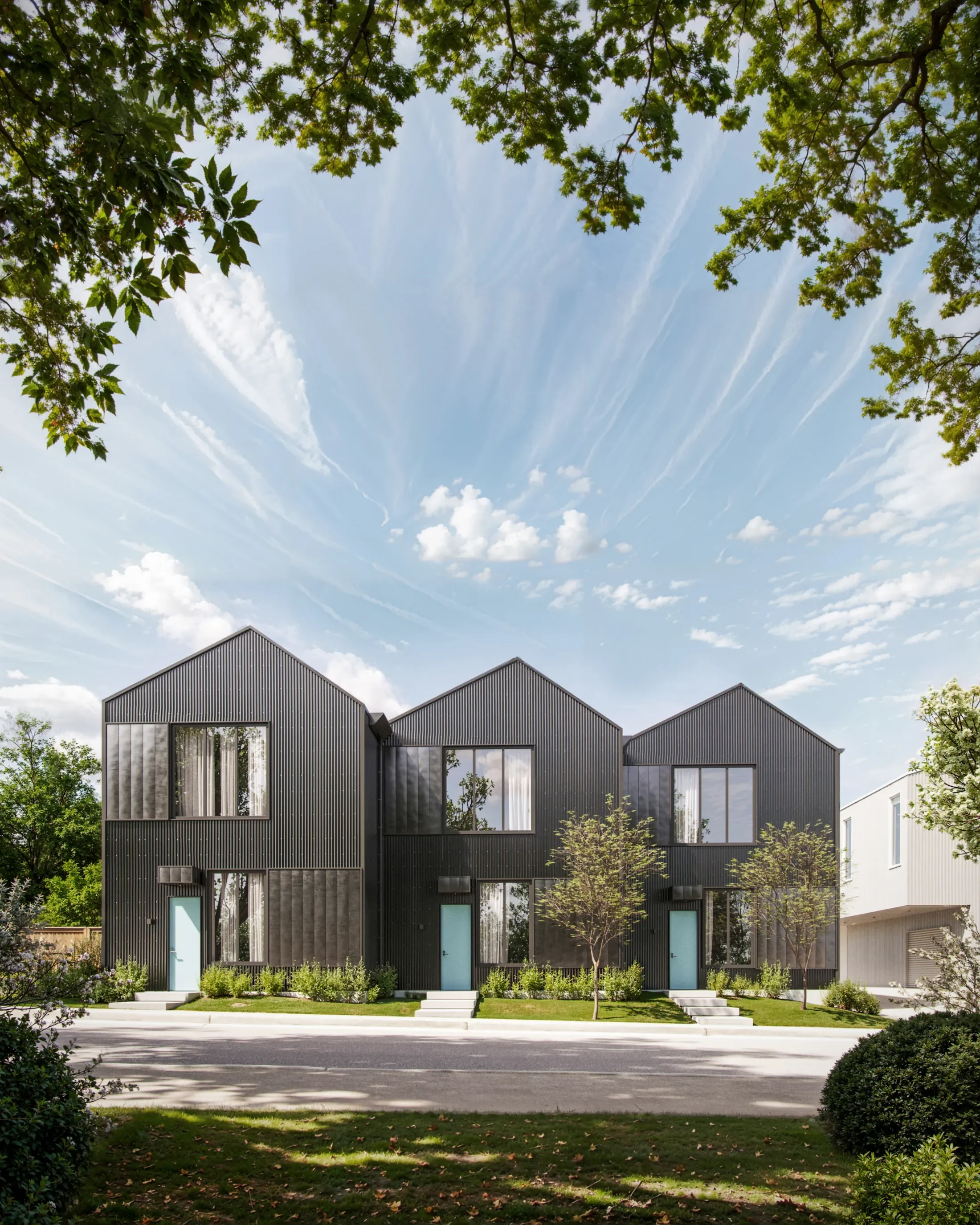 Three modern black duplex houses with peaked roofs and light blue doors, set in a landscaped neighborhood with trees and bushes under a partly cloudy sky.