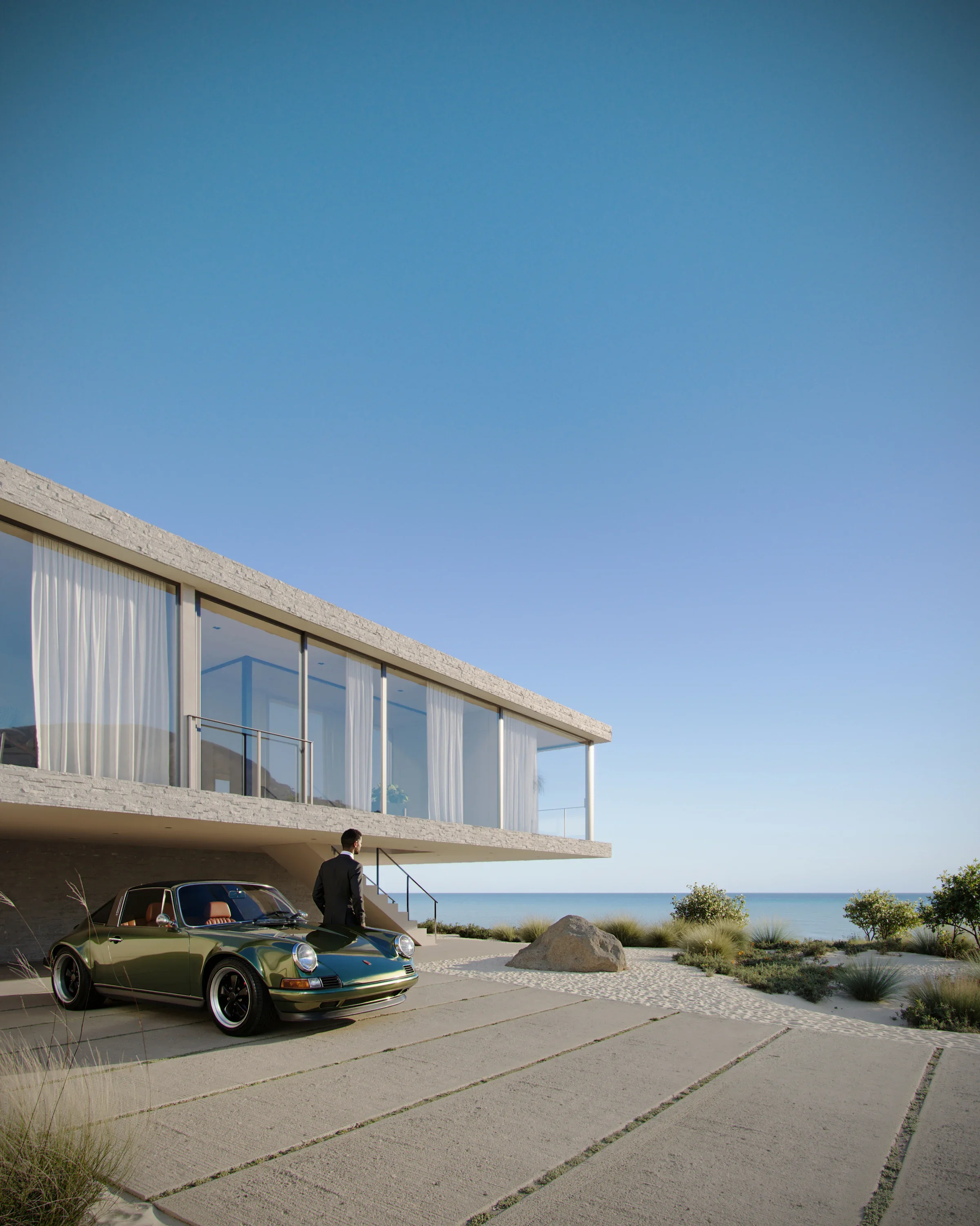 A man in a suit standing next to a vintage green Porsche parked outside a modern beachfront house with large glass windows and white curtains, overlooking the ocean under a clear blue sky.