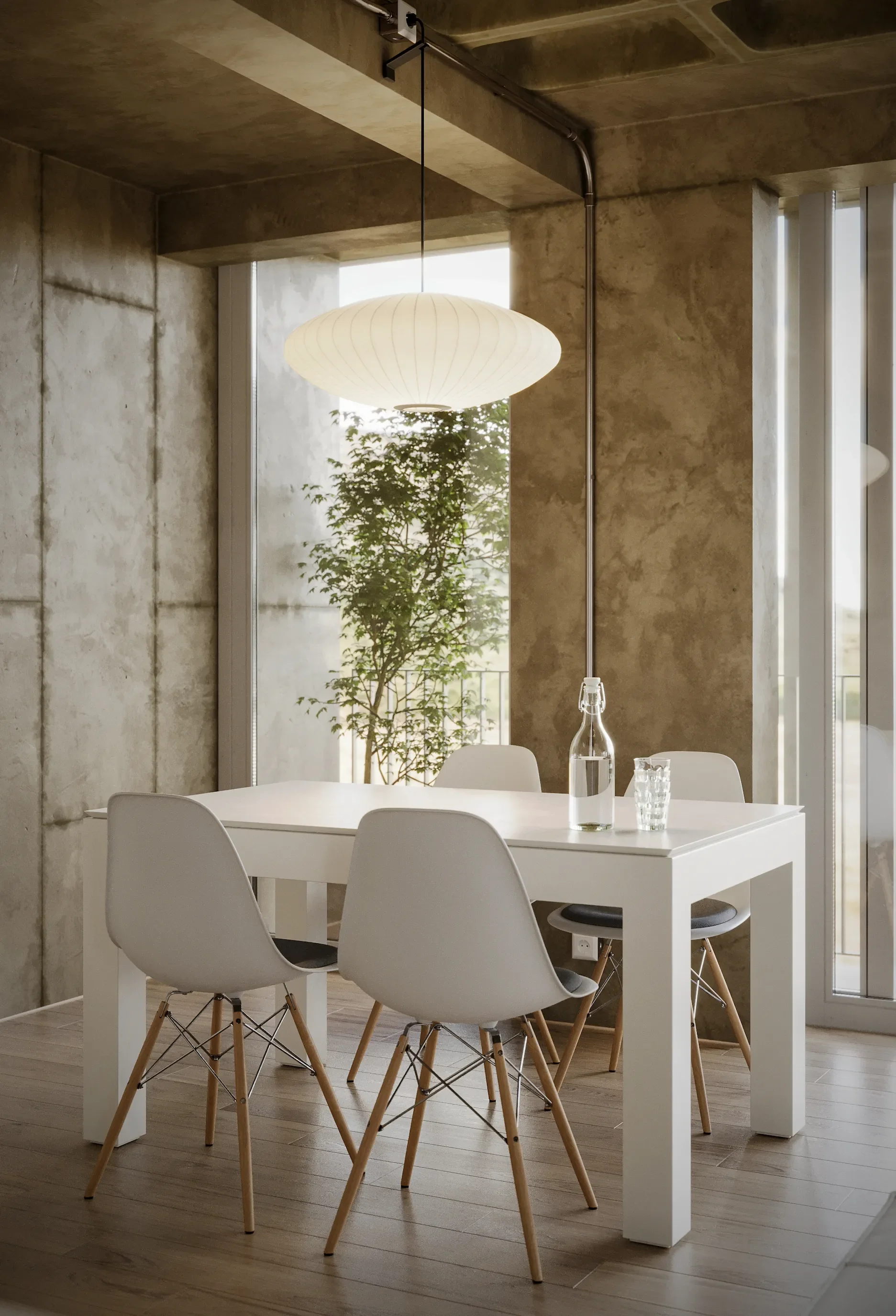 Minimalist dining area with a white table, four white chairs with wooden legs, a glass water bottle, a glass, and a modern pendant light hanging from a concrete ceiling.