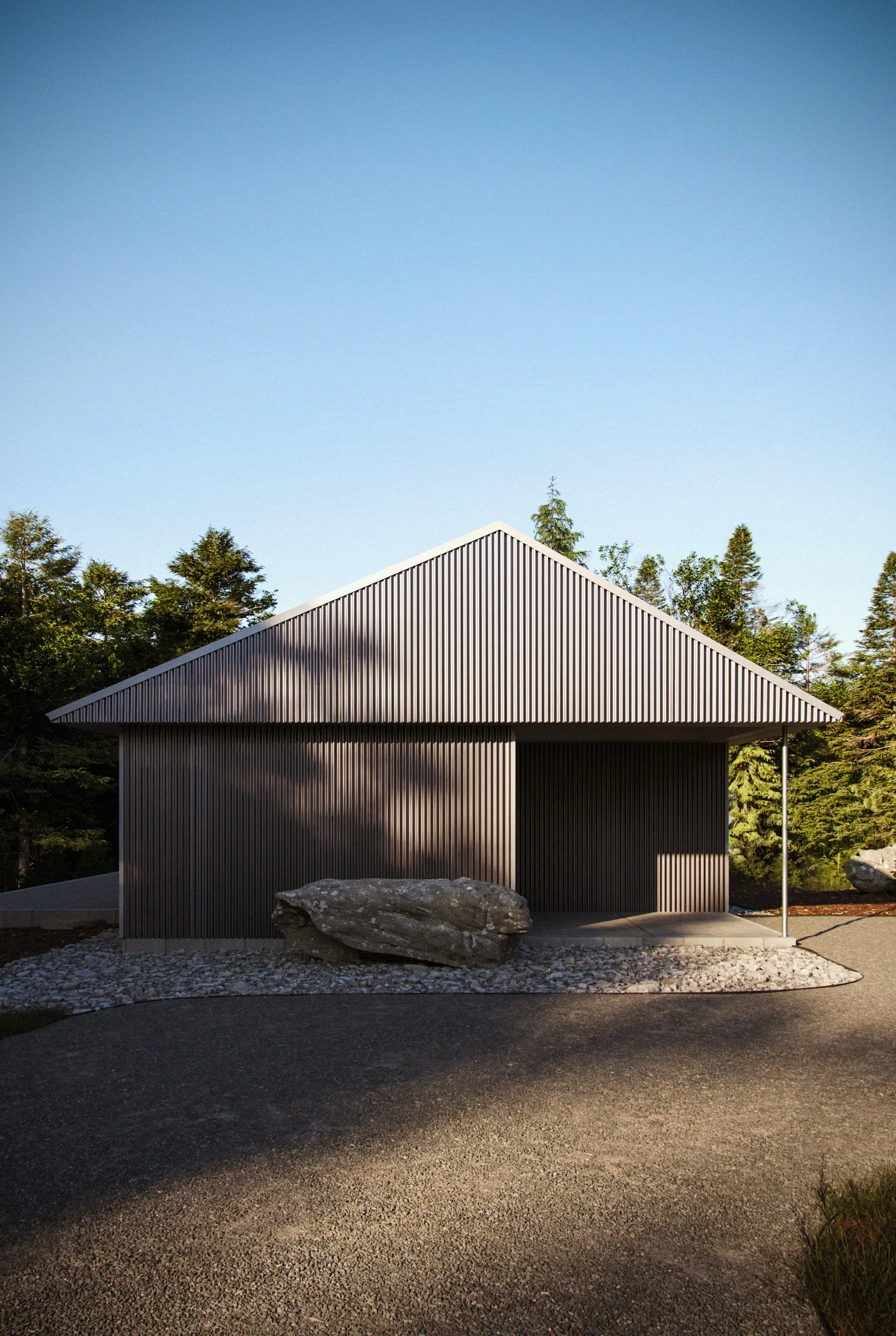 Modern building with dark metal siding, large rock in front, and a gravel area. Surrounded by green trees and under a clear blue sky.