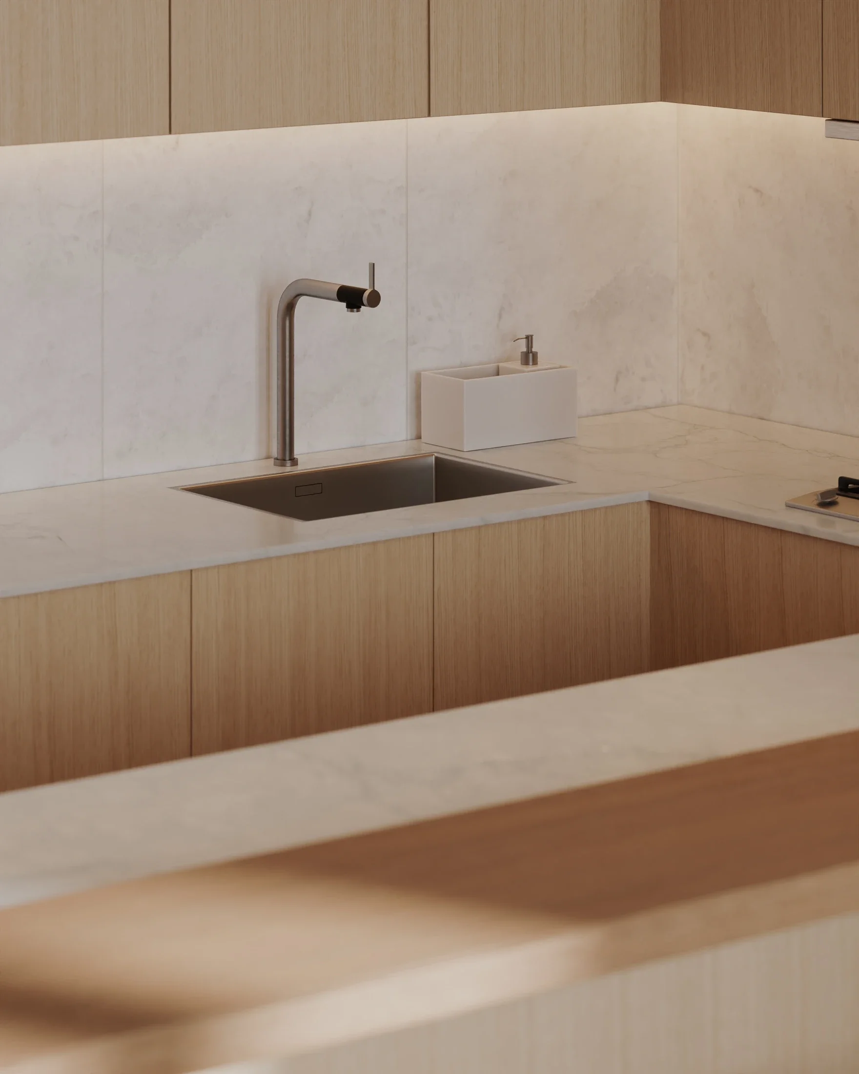 Modern kitchen with marble countertops, a stainless steel sink, a tall faucet, a white soap dispenser, and wooden cabinetry.