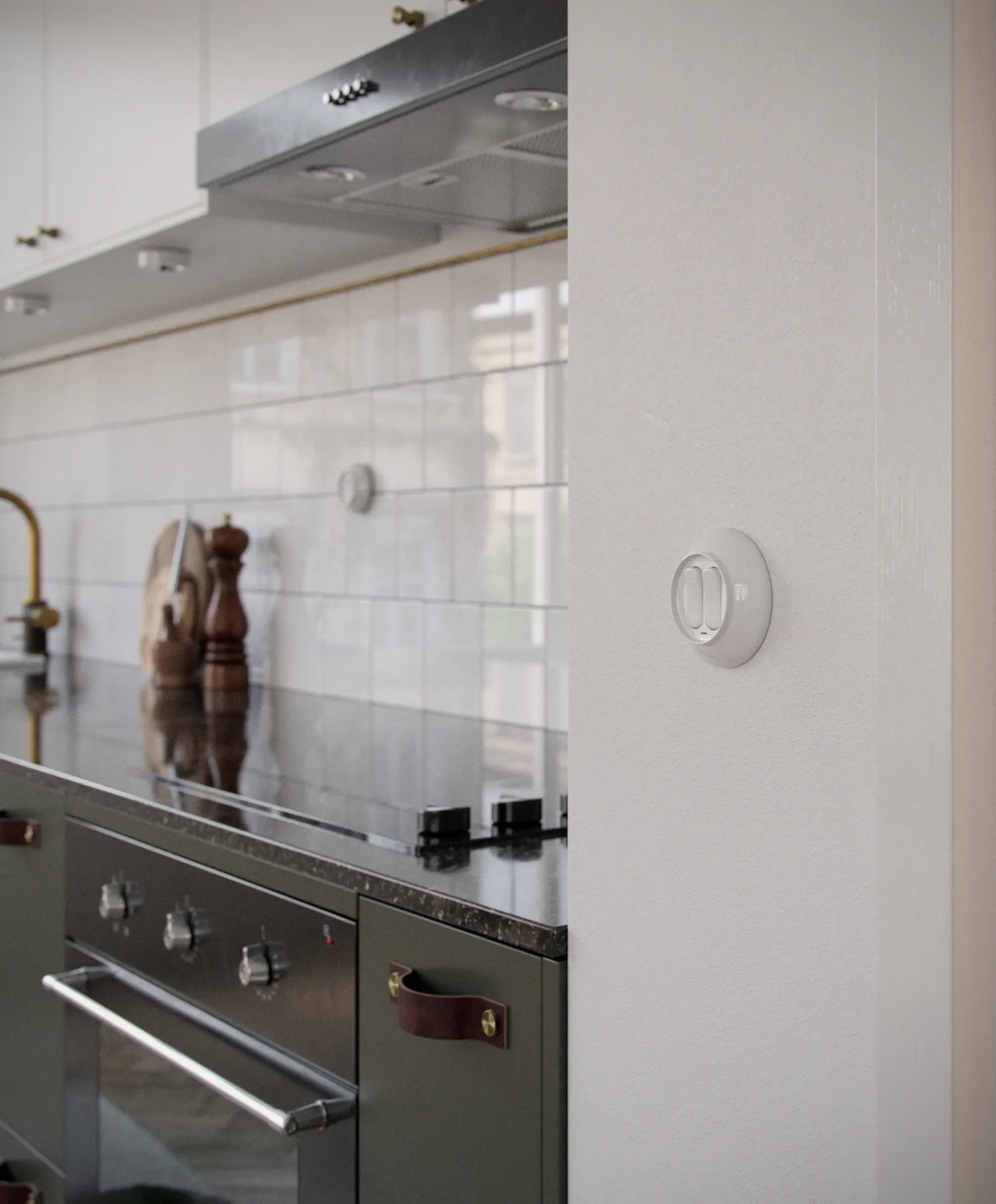 Kitchen wall with a thermostat on the wall, a stove with knobs, a range hood, and a countertop with a wooden pepper grinder and a beige bag.