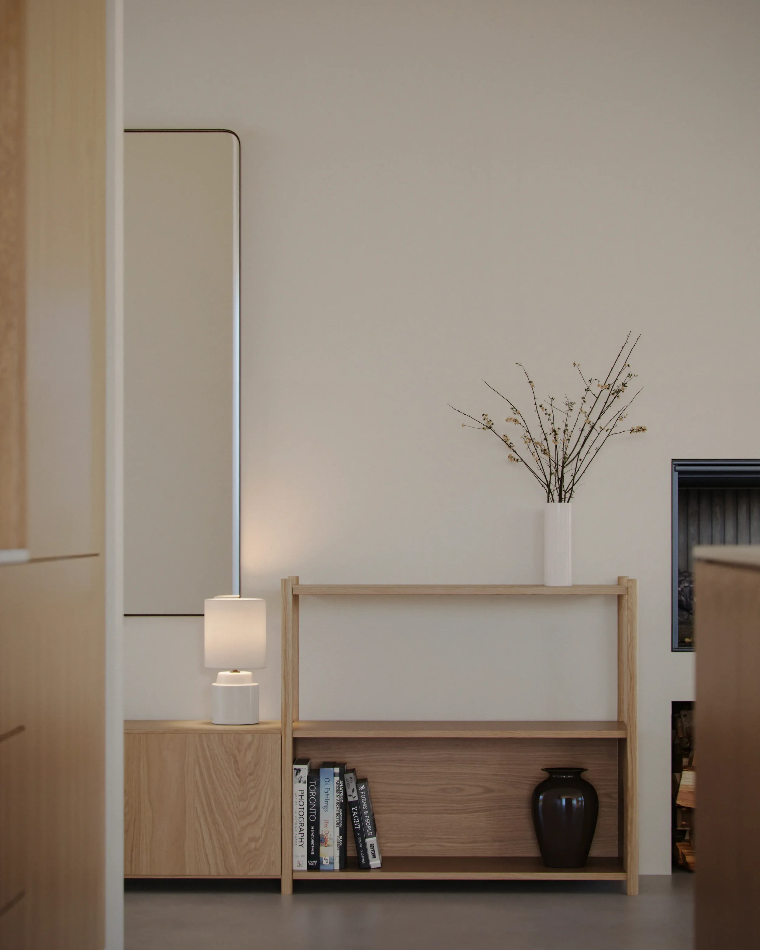 Minimalist living room shelf with books, a black vase, and a white vase with dry branches, next to a lamp and a fireplace