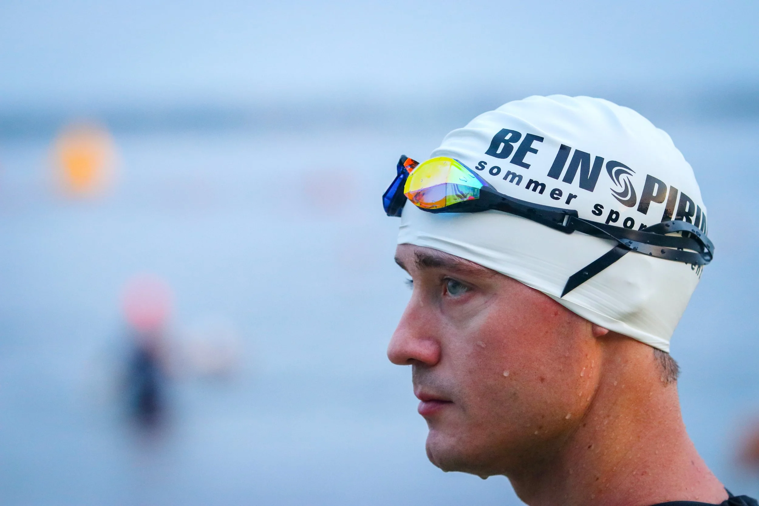A man wearing a swim cap with goggles getting ready for a triathlon