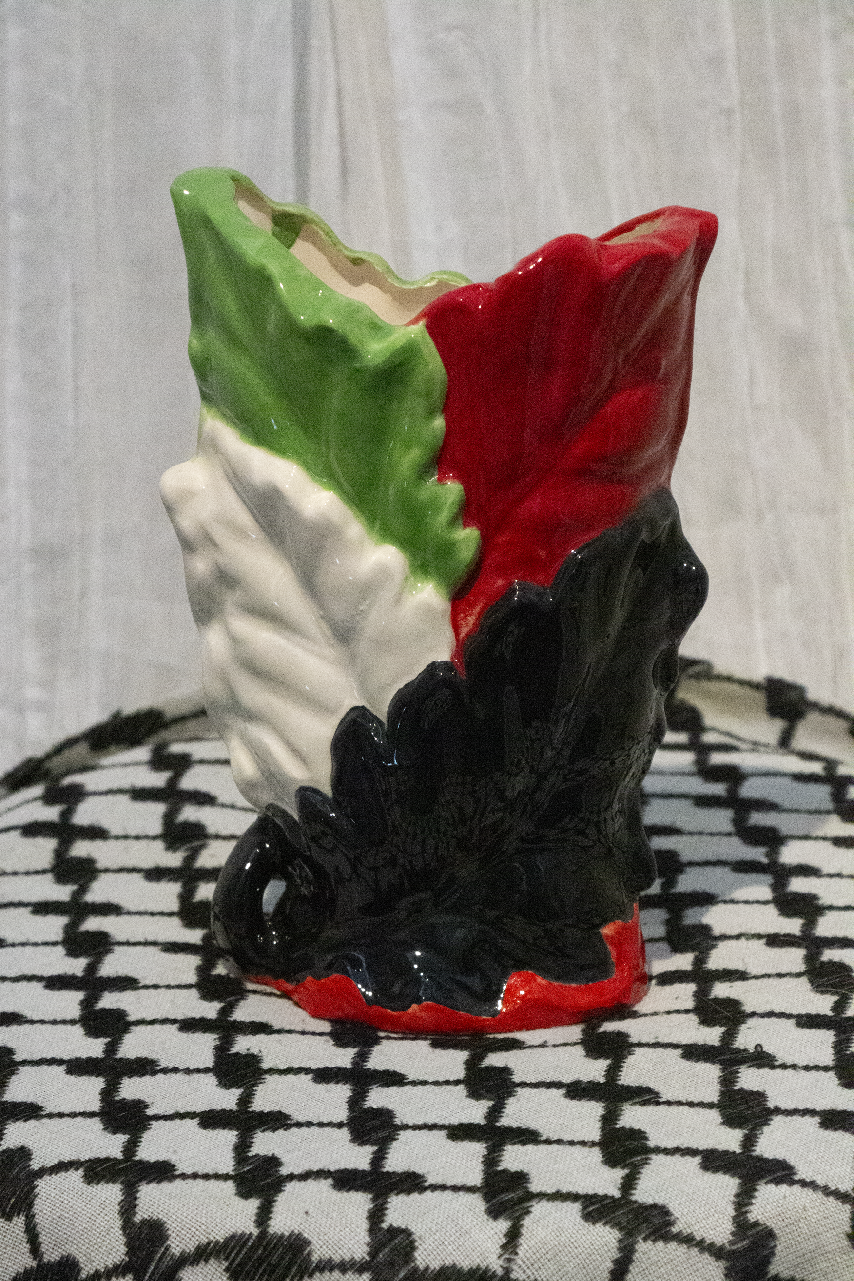 "Vase 5", a small ceramic vase of leaves painted in green, black, and red to represent the Palestinian flag